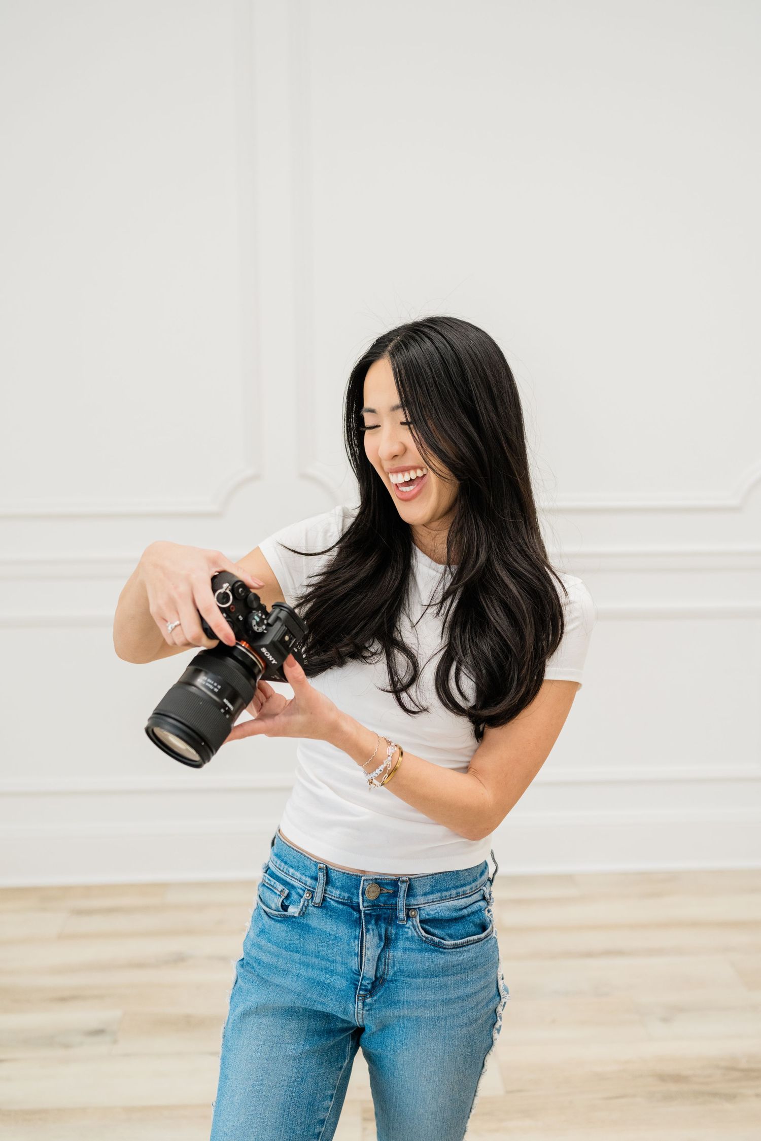 Professional photographer in casual attire reviewing photos on camera in bright studio setting.