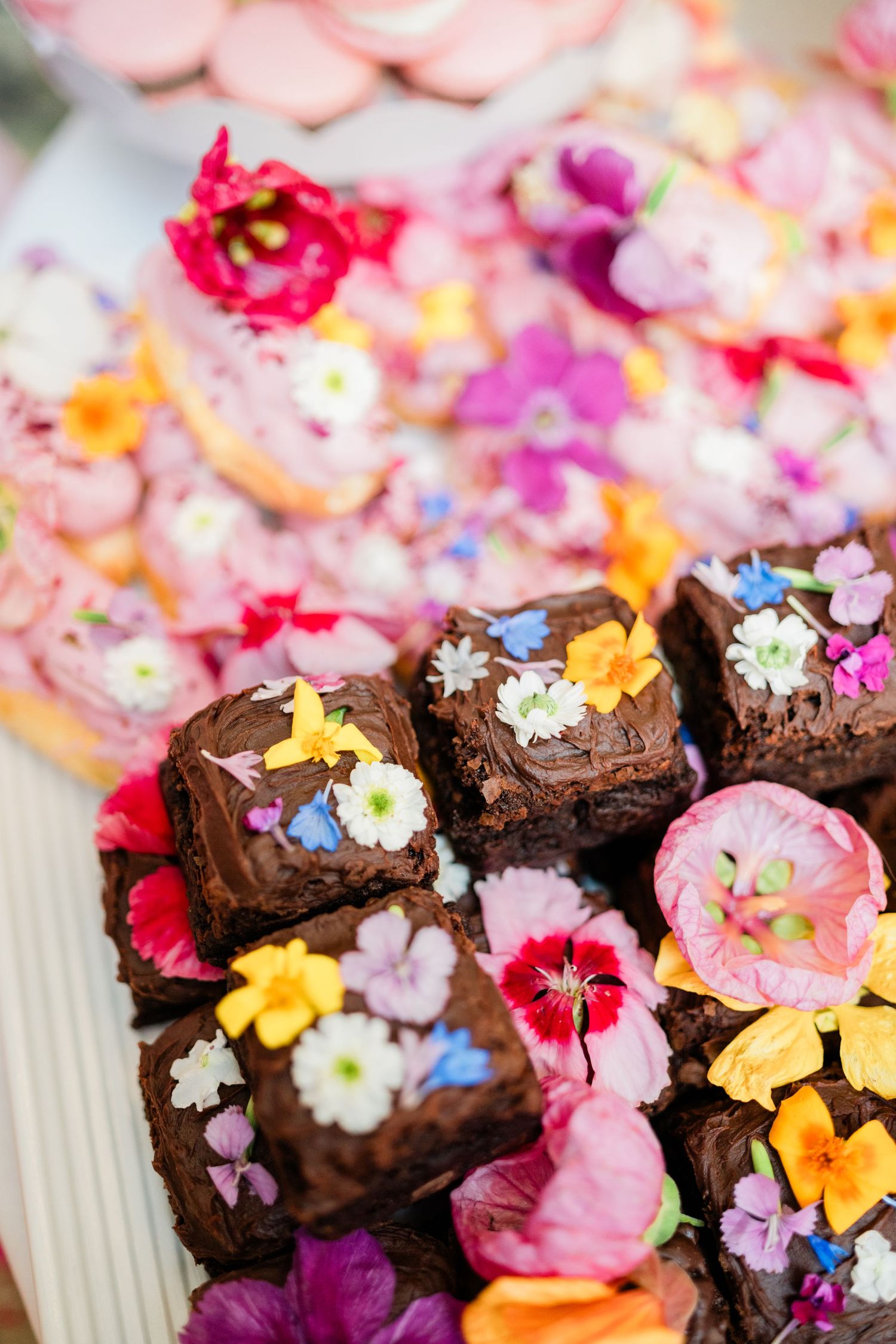 Chocolate brownies decorated with colorful edible flowers for special occasion.