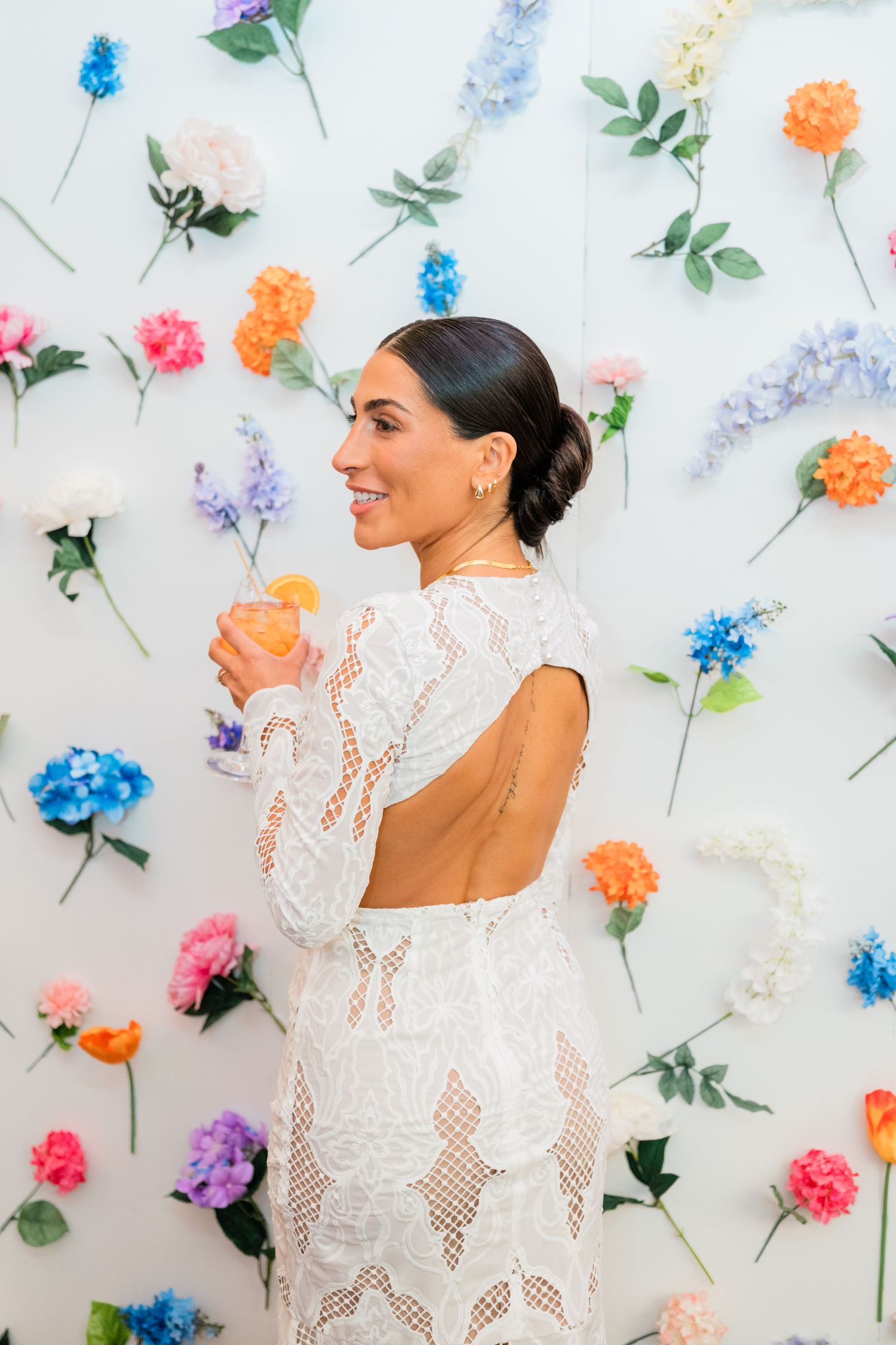 Bridal fashion against white wall decorated with colorful flower installations.