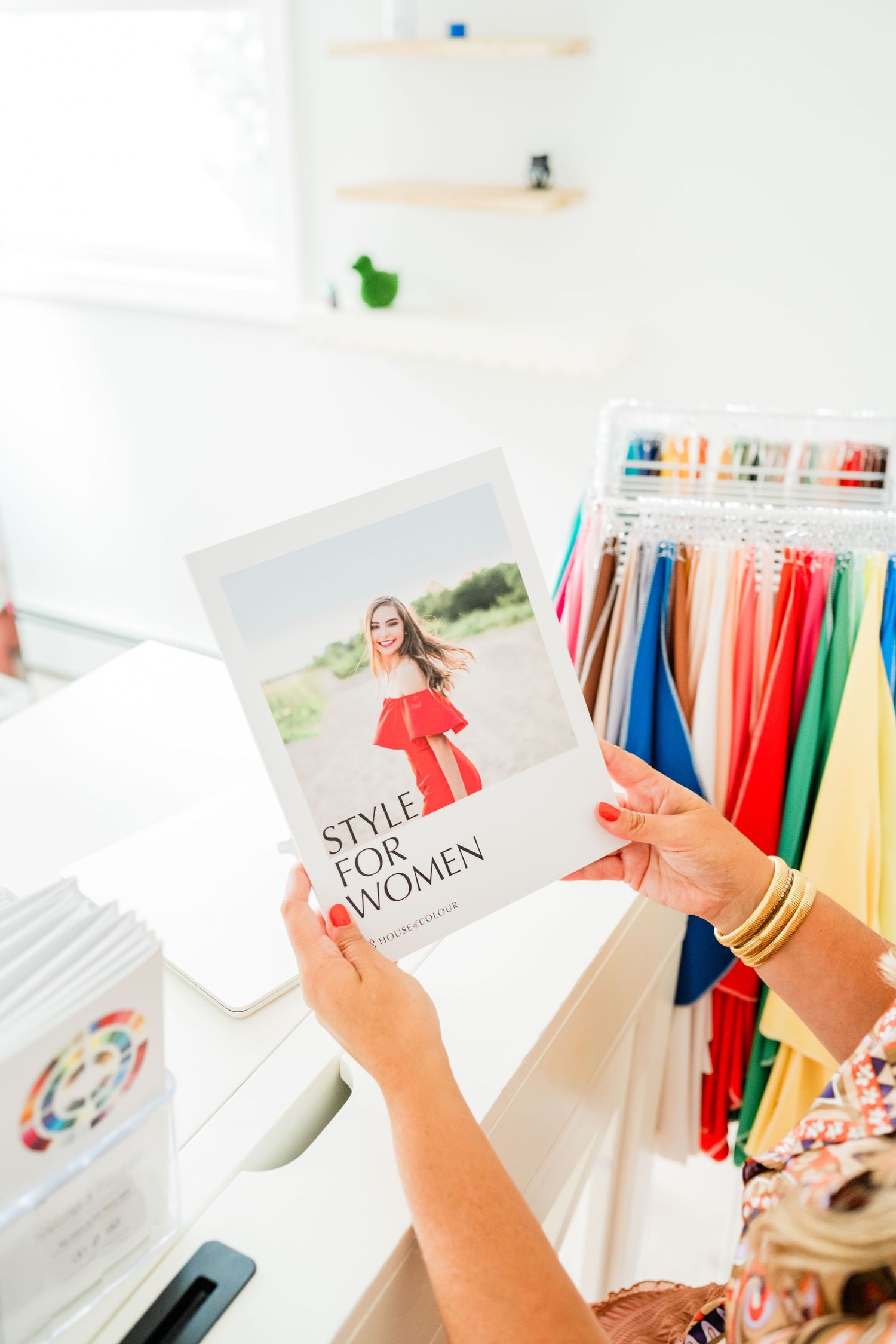 Style guides and fashion cards displayed with colorful clothing rack in background.