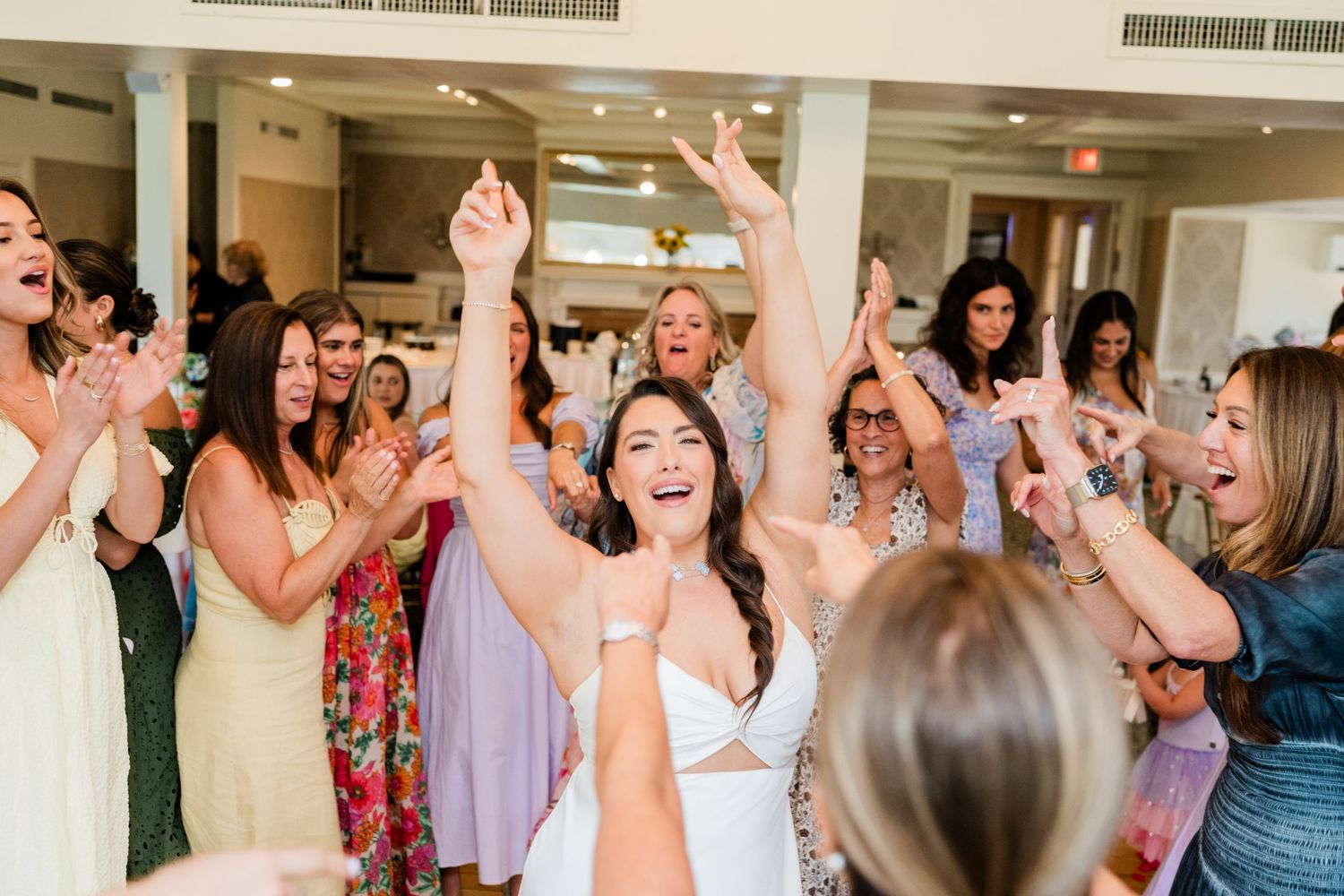Wedding guests celebrating with raised arms and excited expressions at a reception.