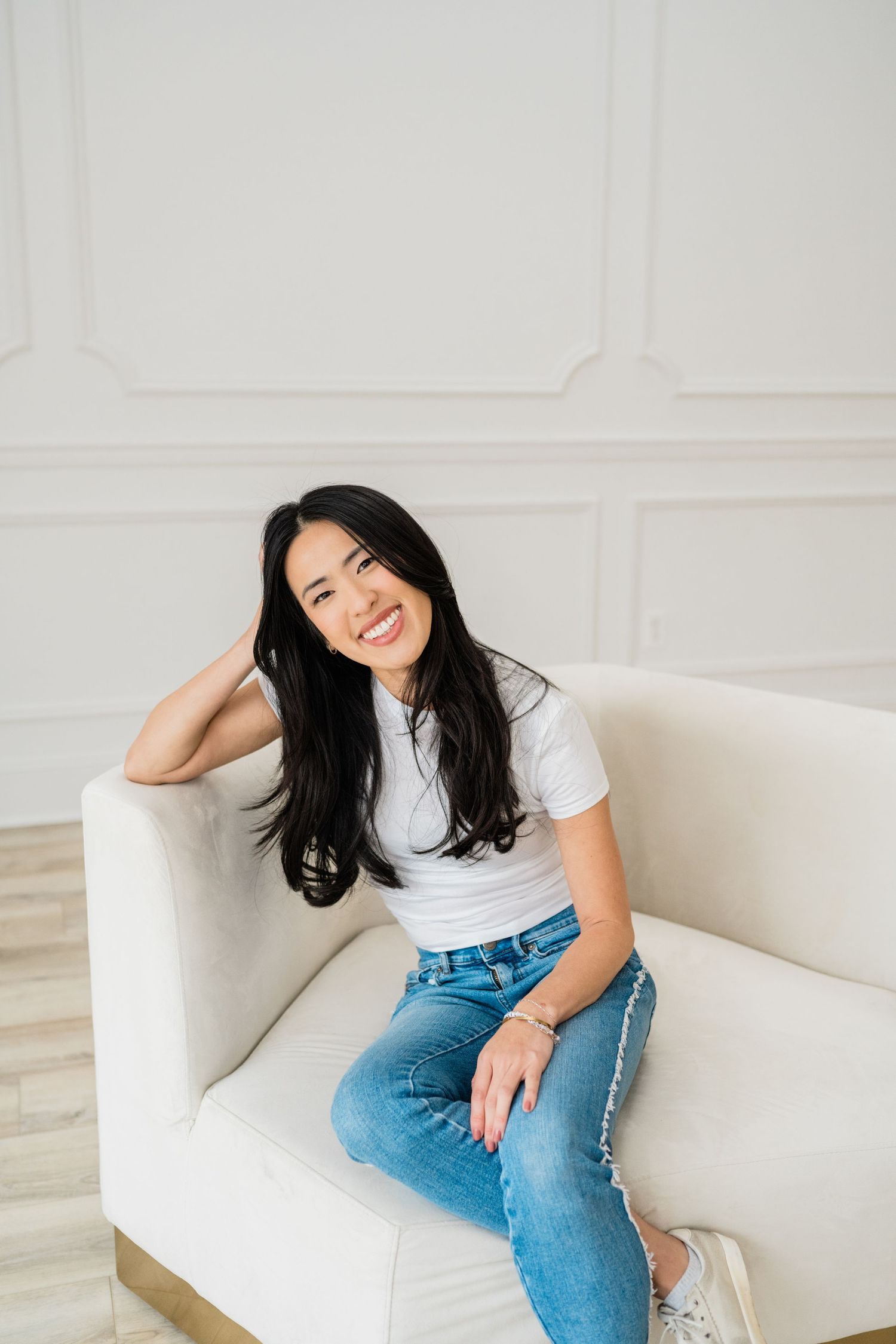 Casual portrait session on a white couch in a minimalist setting.