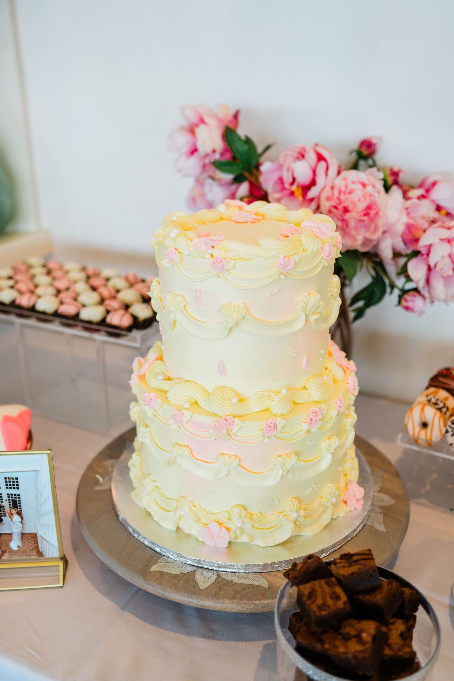 White wedding cake with delicate pink ruffled details and fresh flowers on display.