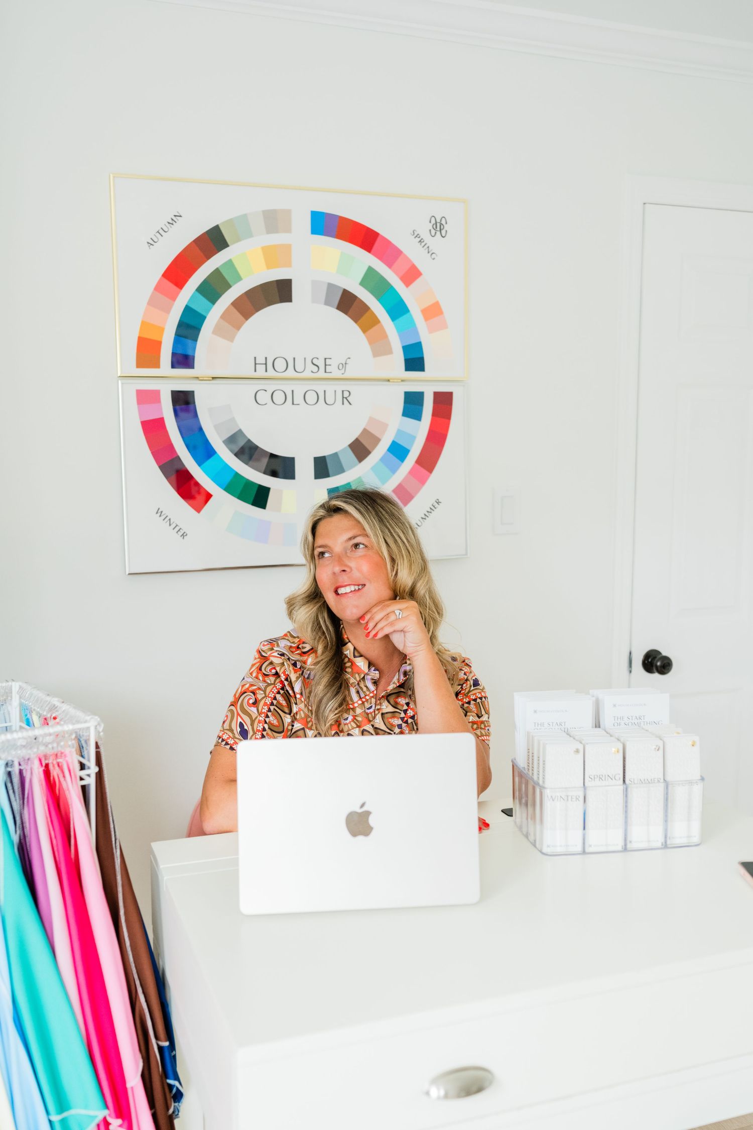 Professional workspace with color wheels, laptop and clothing rack in modern office setting.