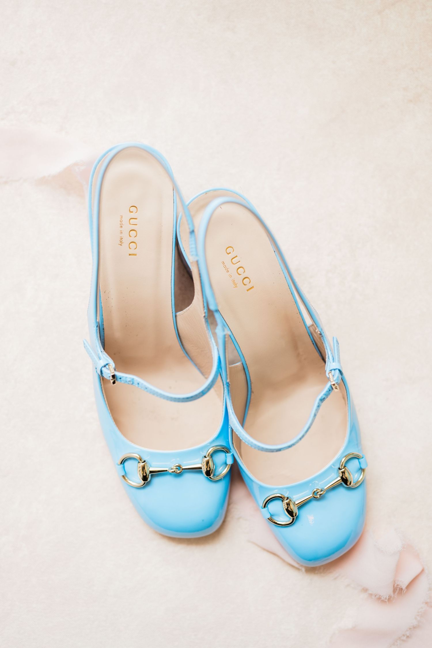 Light blue ballet flats with gold hardware details on a pale background.