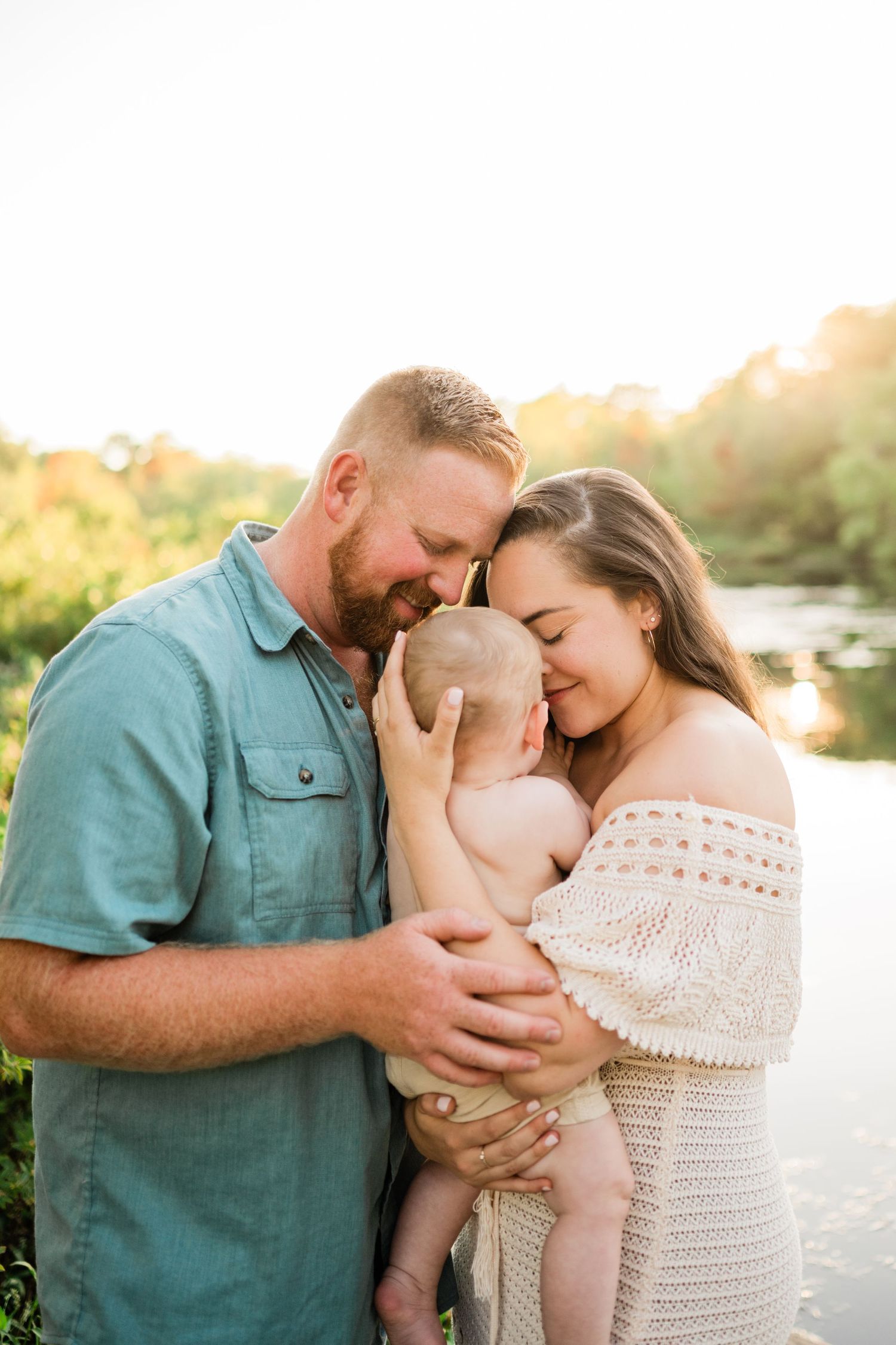 Family portrait session at sunset showing tender moments between parents and baby.