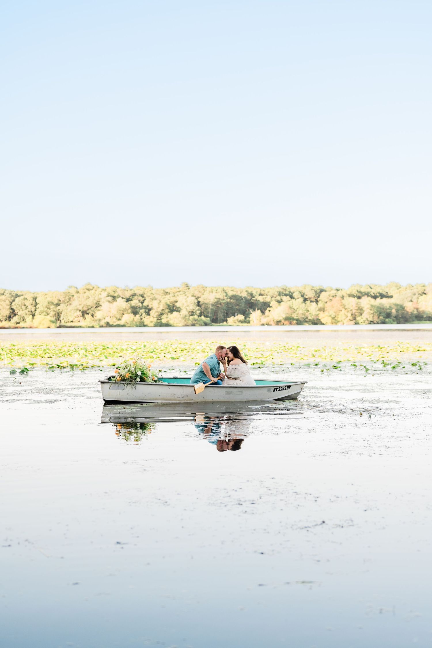Romantic boat photoshoot on a serene lake with distant landscape views.