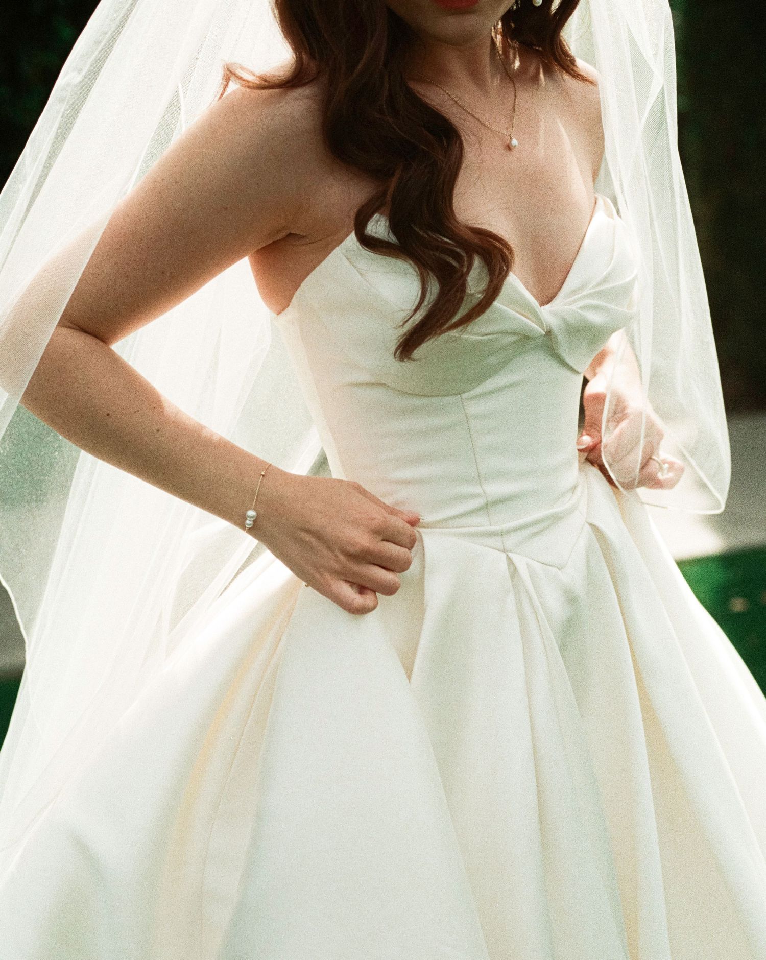 Close-up view of an elegant white strapless wedding dress with sweetheart neckline and flowing veil.