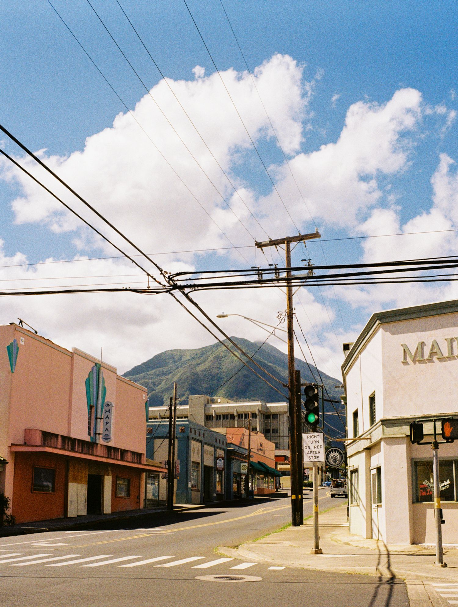 Small town street with power lines and mountain views in Hawaii.