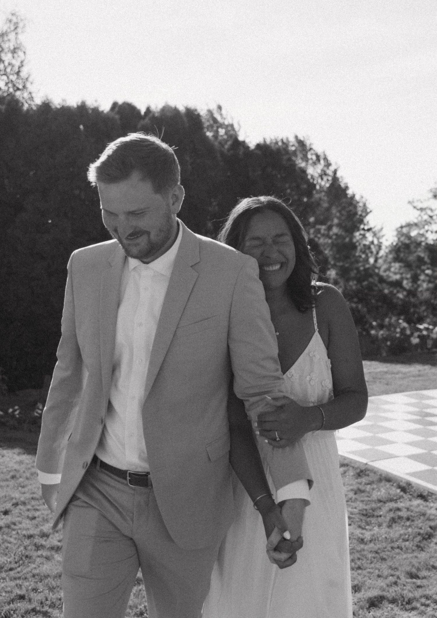 A couple laughing together outdoors dressed in formal attire.