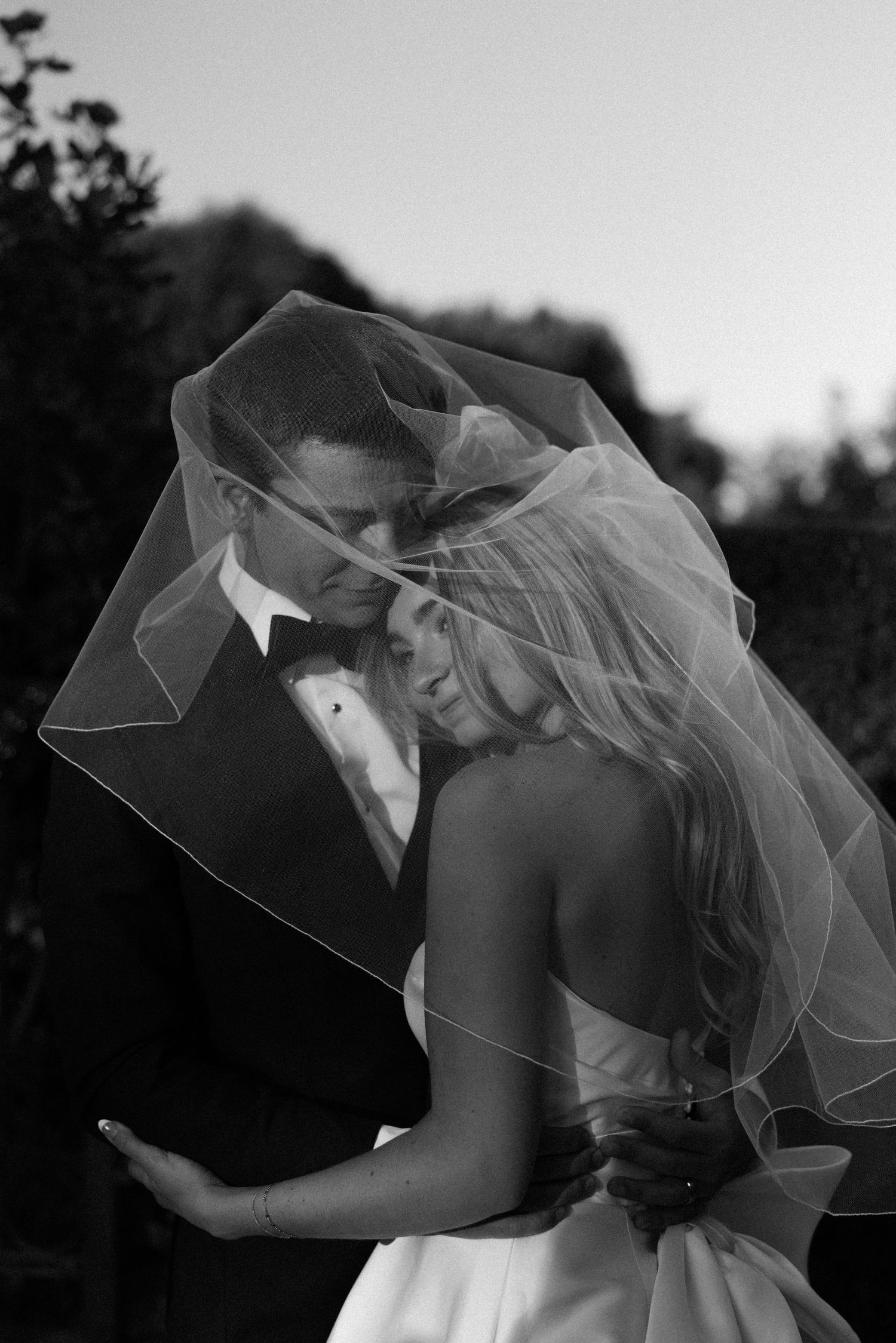 Romantic black and white portrait with flowing bridal veil in gentle breeze.