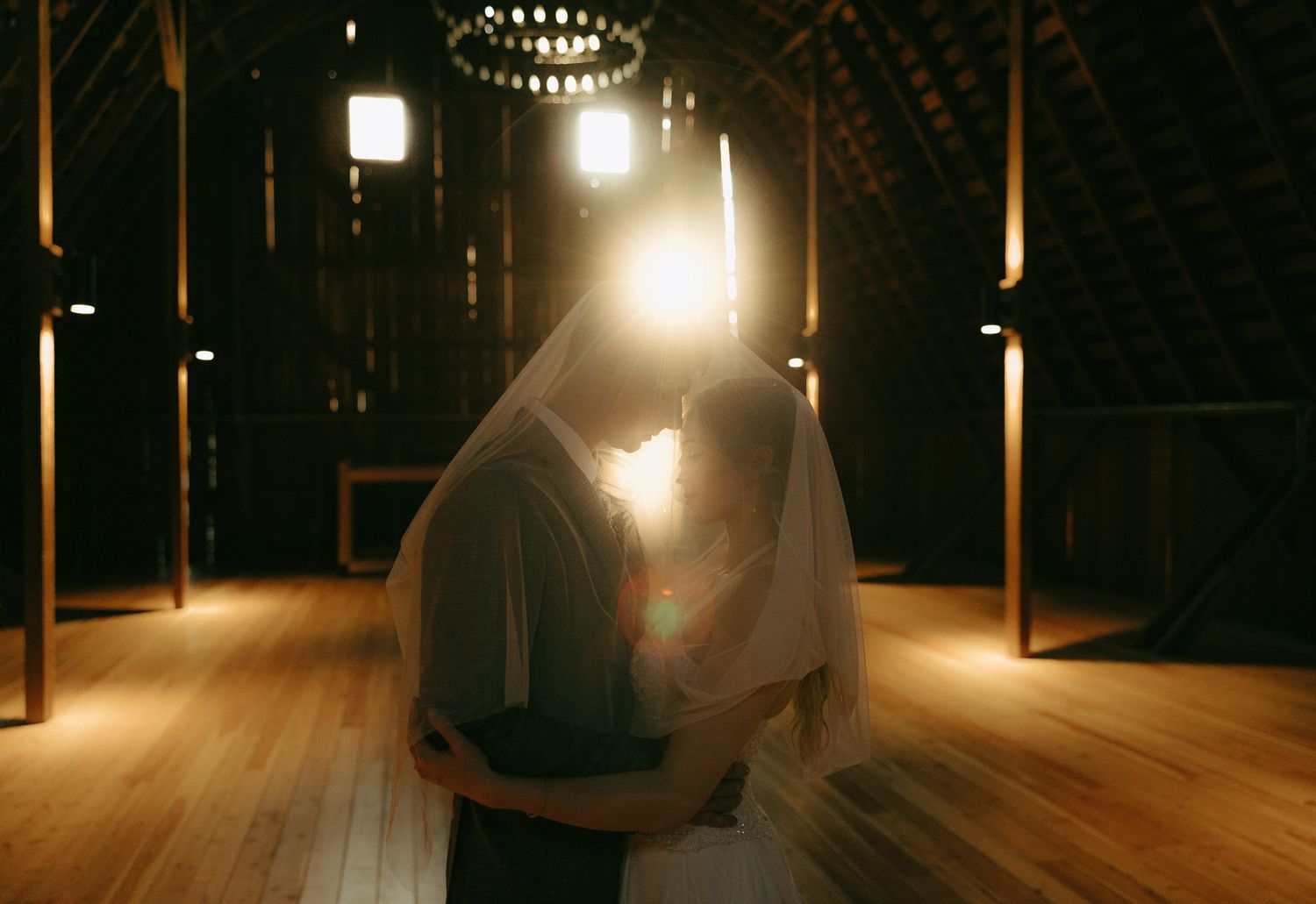 A dramatic first dance silhouette in a rustic barn with warm lighting.