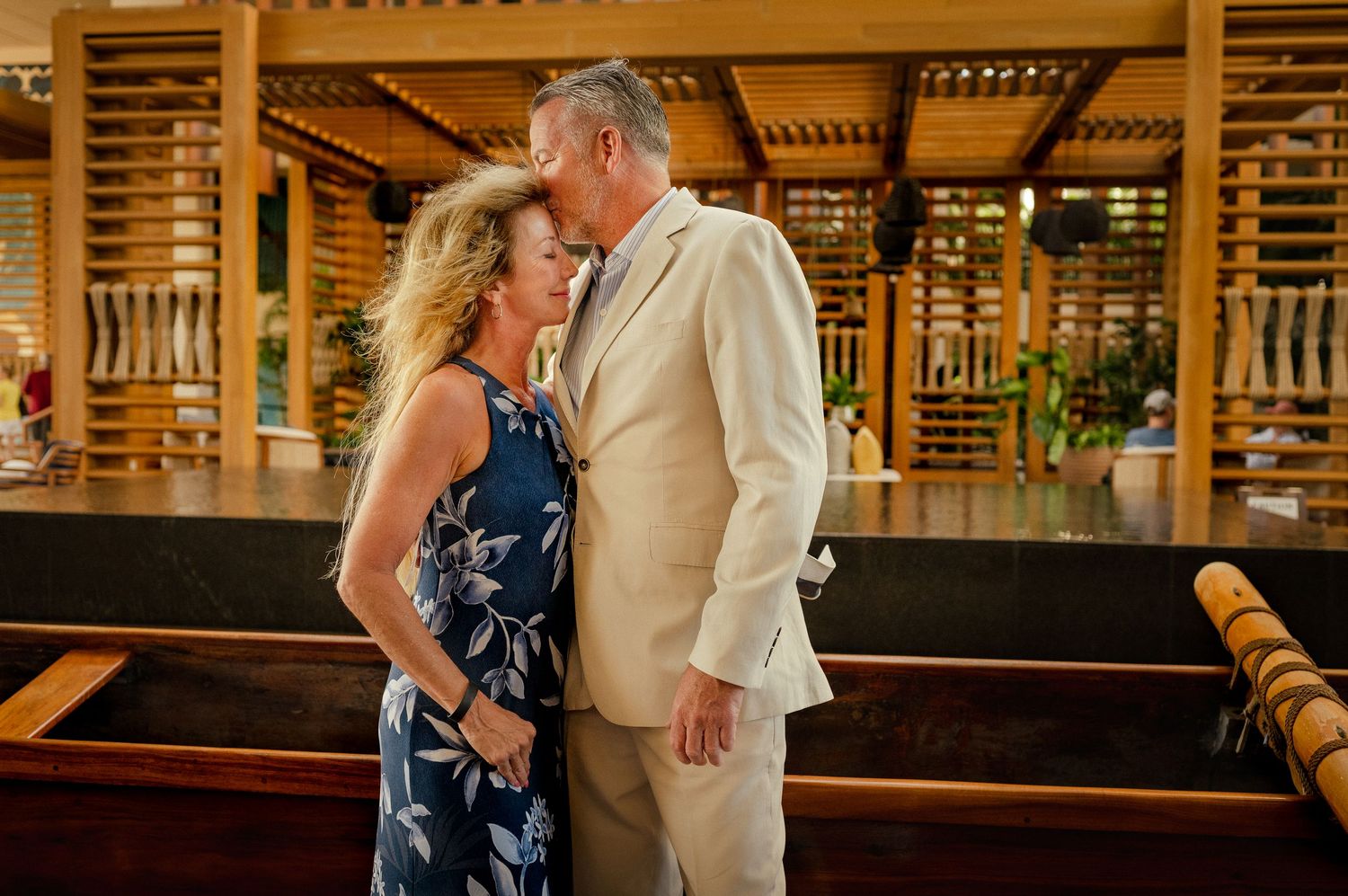 Couple sharing a romantic moment in an elegant tropical resort restaurant with wooden architecture.