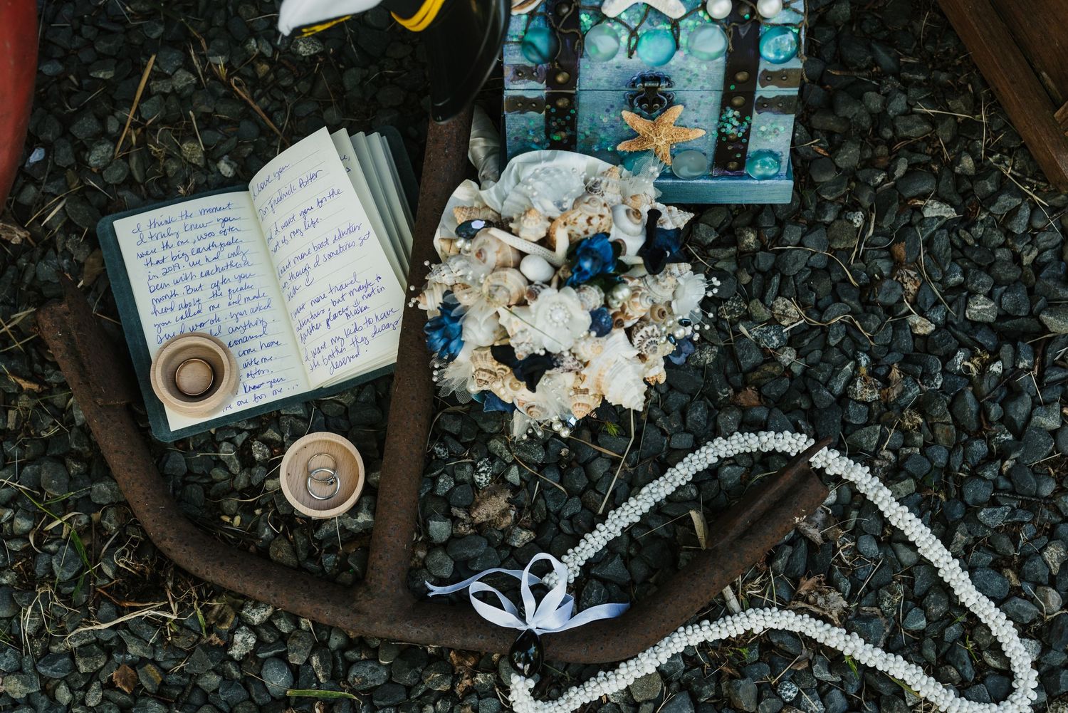 Wedding stationery and delicate floral decorations are artfully arranged on a dark textured surface.