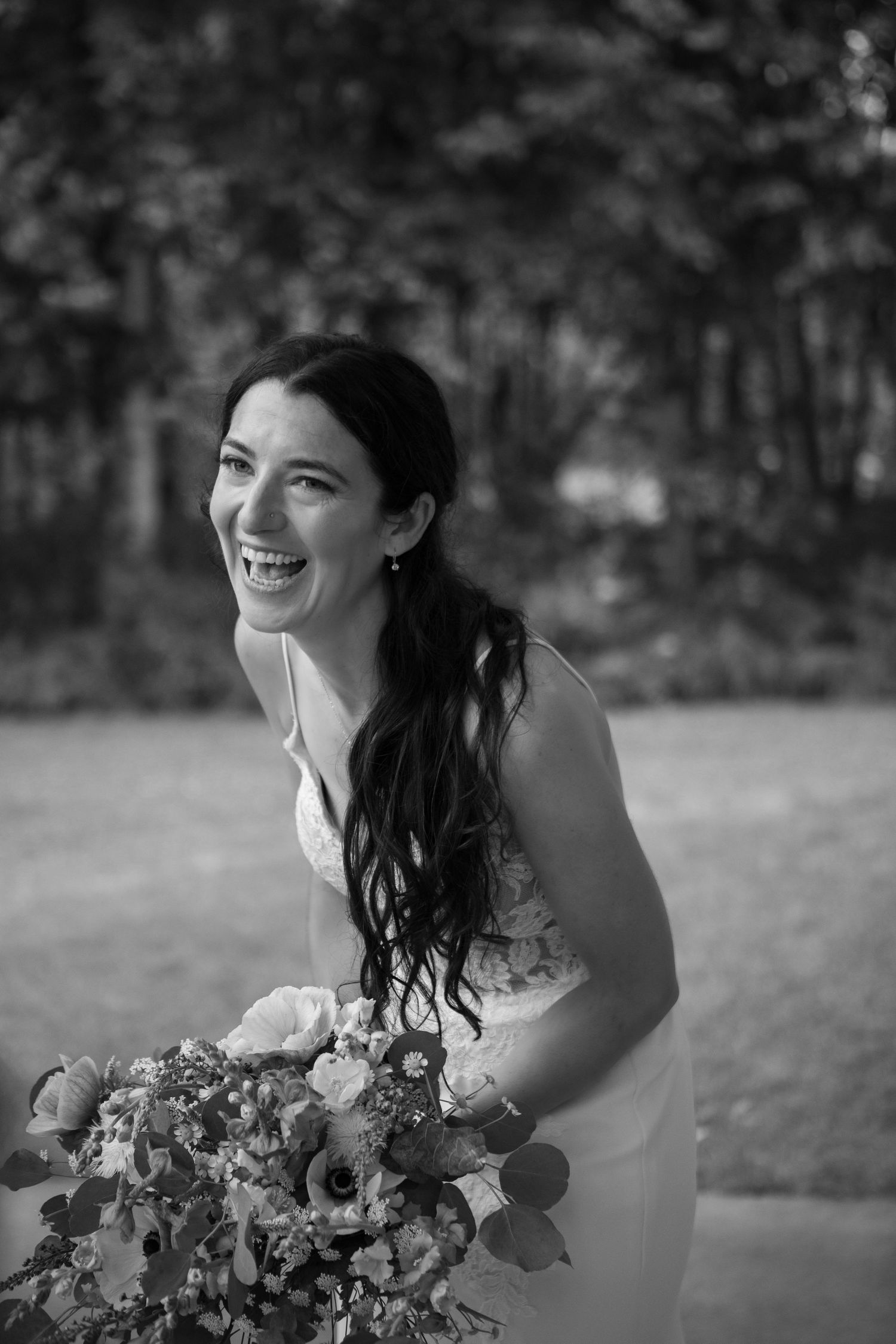 A joyful bride captured in black and white with a beautiful bouquet of flowers.