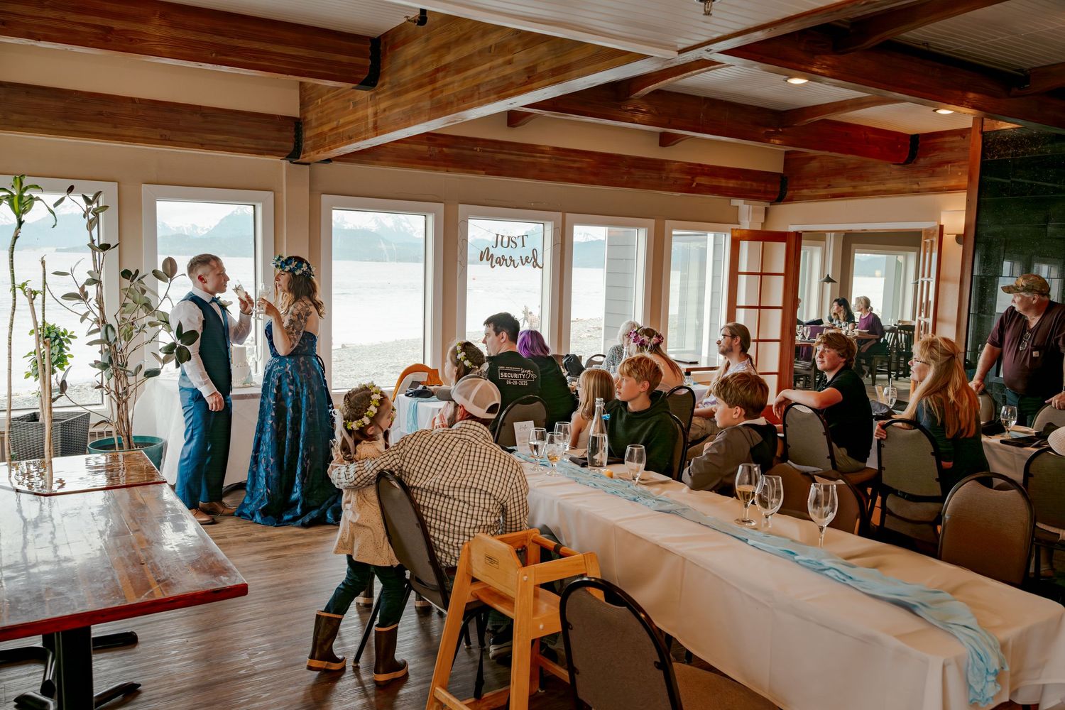 Wedding reception in a lakeside venue with guests seated at tables while the couple shares a dance.
