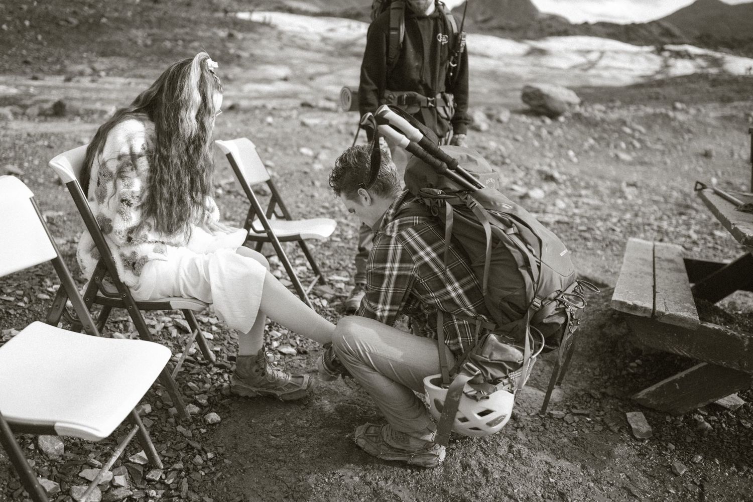 Two people enjoy hiking and camping in a scenic mountain wilderness area with camping gear visible.