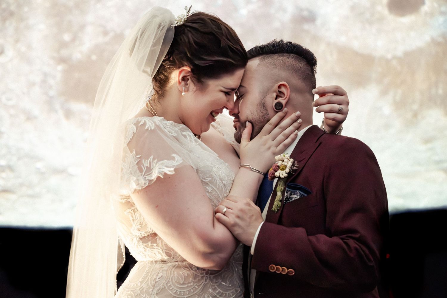 Bride and groom share a romantic forehead touch during wedding ceremony with dreamy moonlit backdrop.