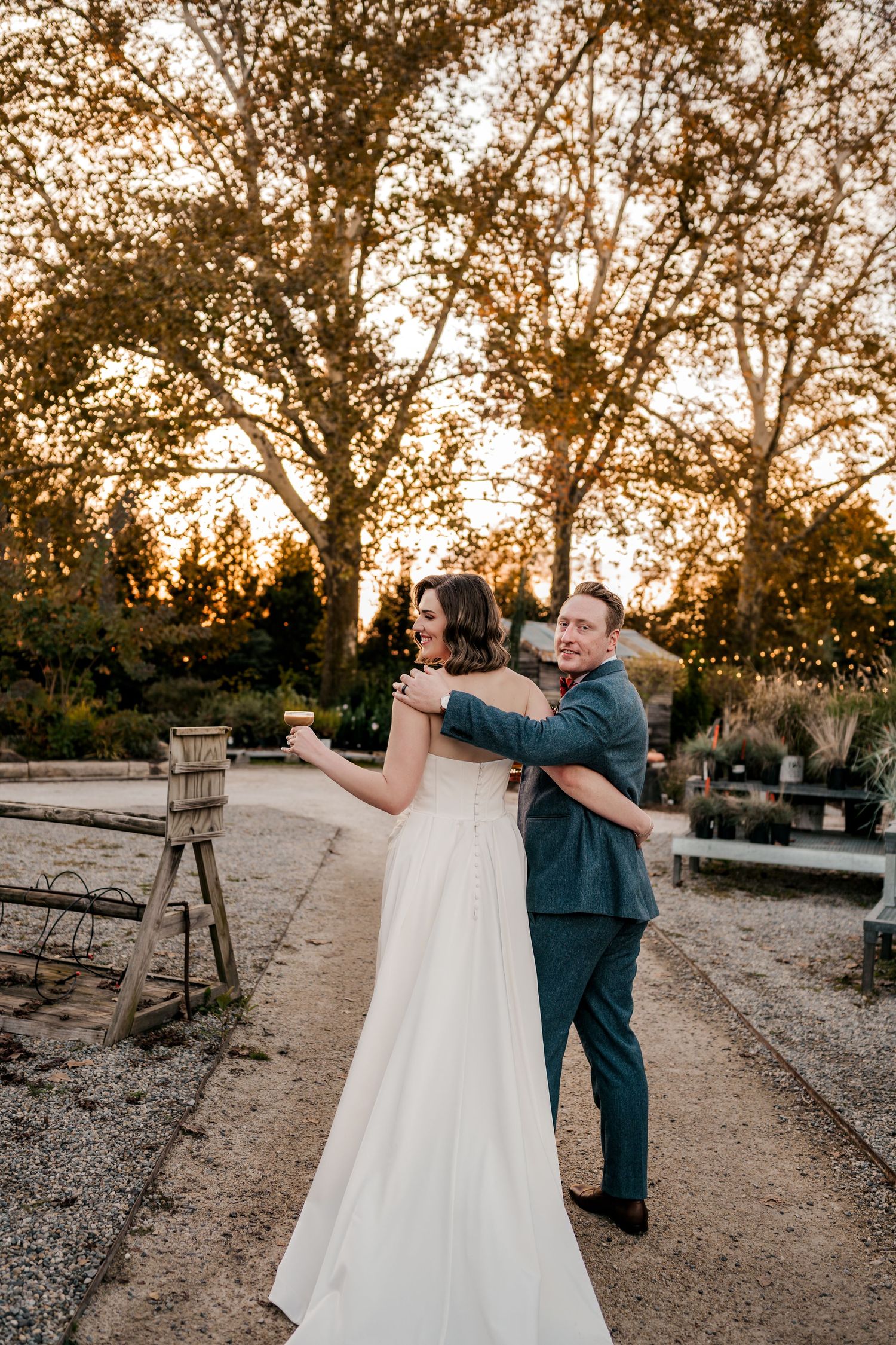 Bride and groom walking away cheersing their espresso martinis at  wedding venue during sunset at Terrain at Styers wedding venue