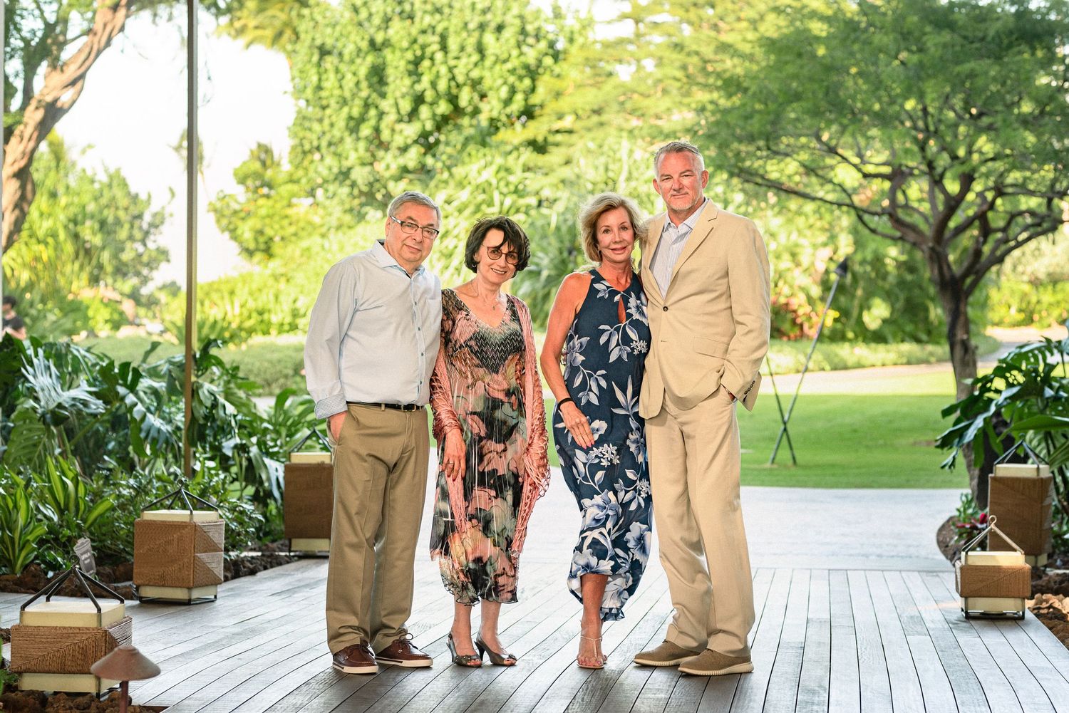 Two couples posing together on a wooden deck surrounded by lush tropical greenery at an outdoor venue.
