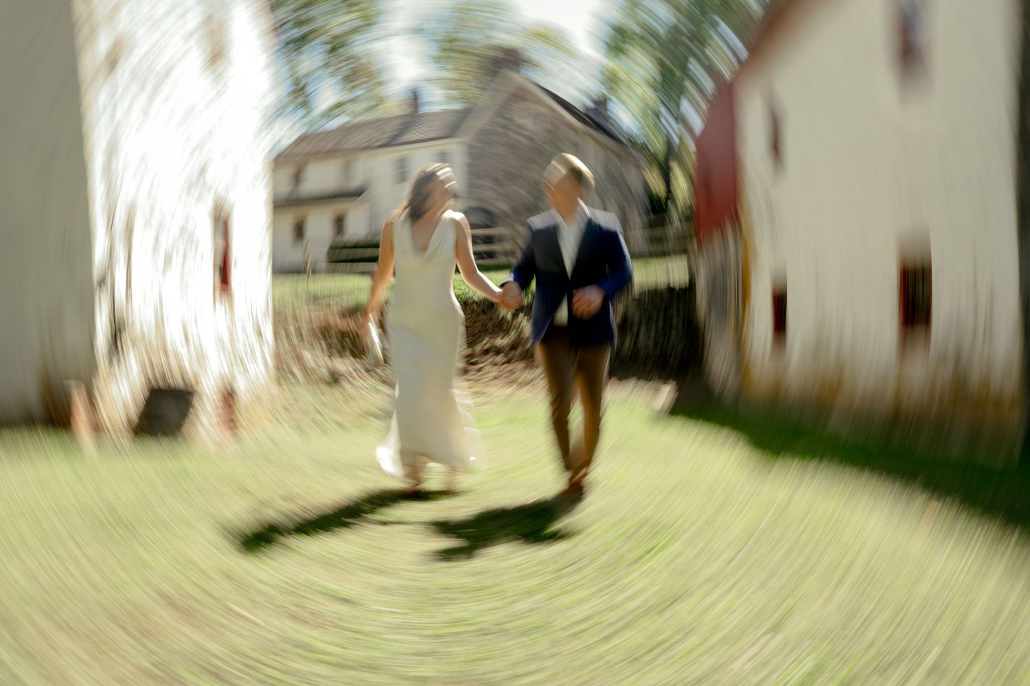 Bride and groom walking hand in hand outdoors on their wedding day with a dreamy blurred effect.