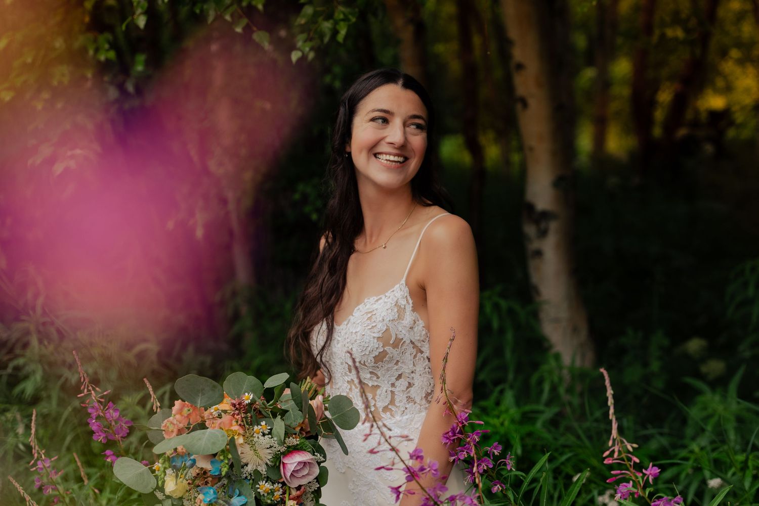 A bridal portrait with soft pink bokeh effect and natural forest backdrop.