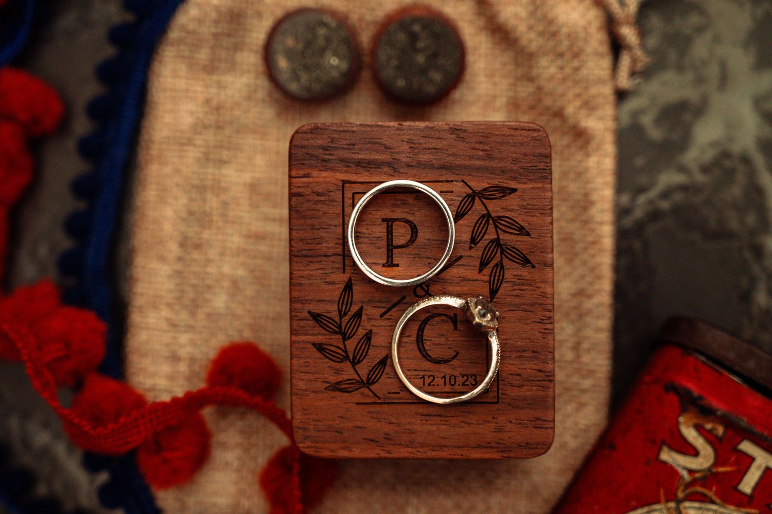 Wedding rings displayed on a wooden box with custom monogram design.