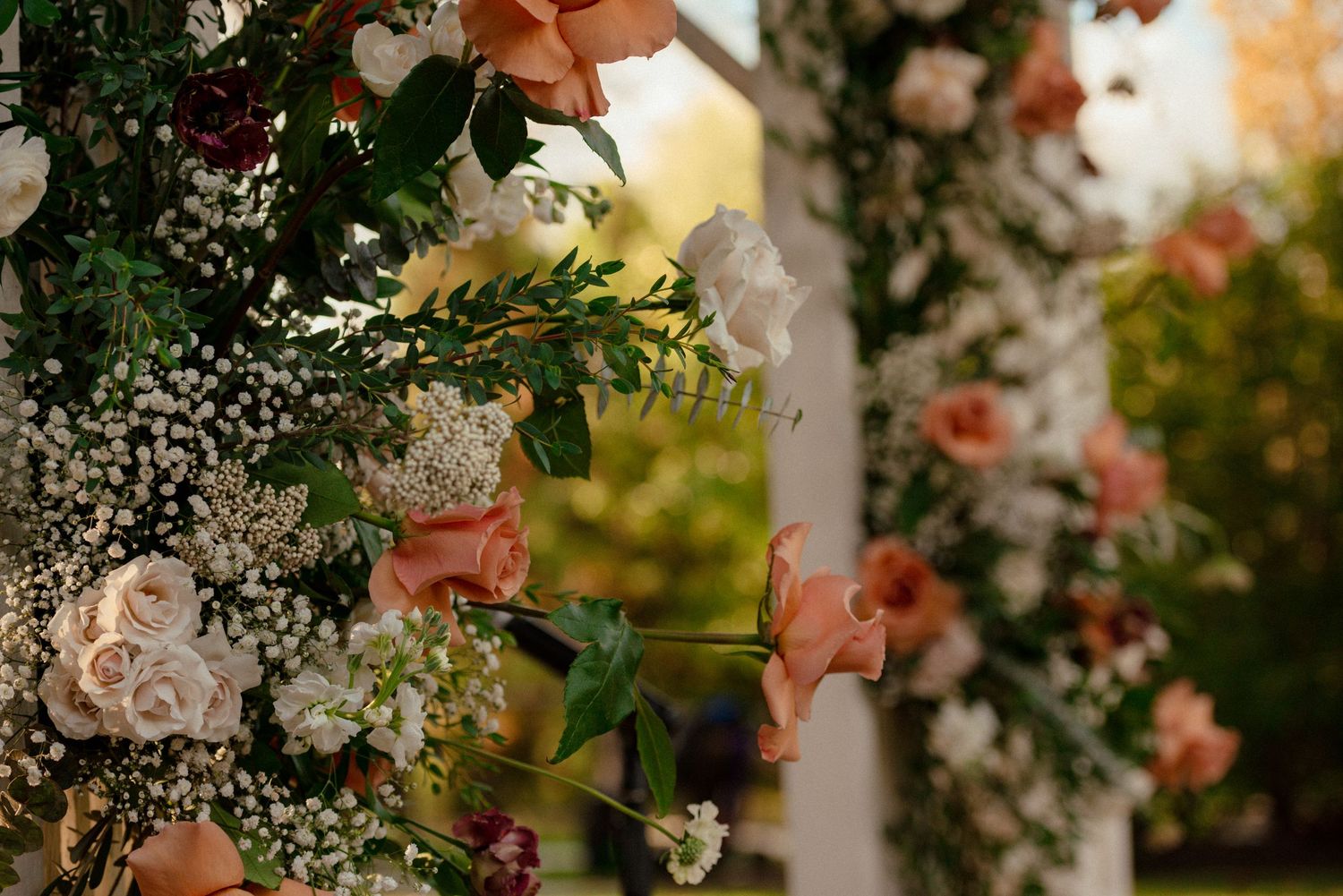 Delicate pink roses and white baby's breath flowers create a romantic floral arrangement against a blurred garden background.
