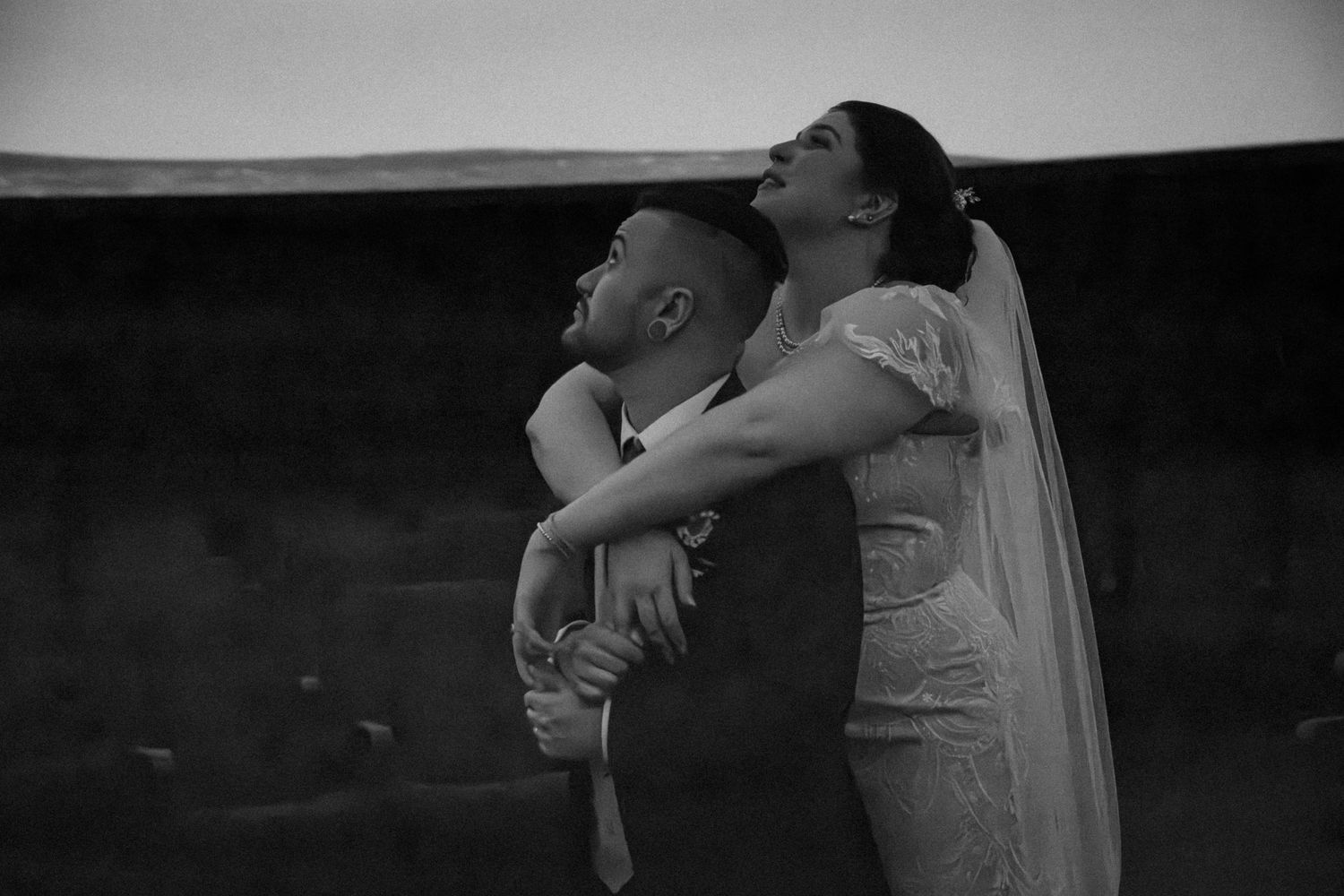 Black and white photo of a bride and groom embracing tenderly during their wedding ceremony.