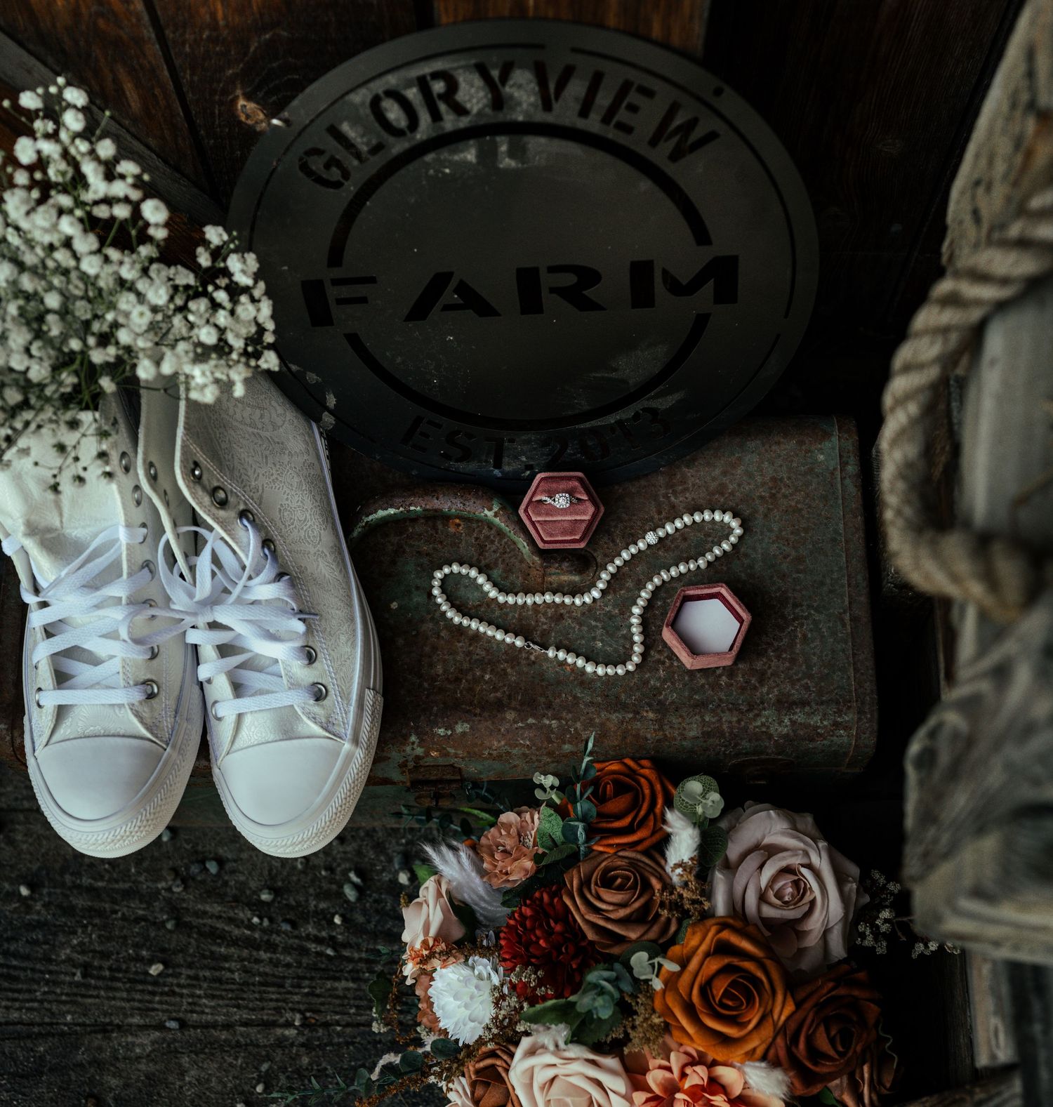 Wedding details flatlay with white sneakers, rings, and roses against rustic Gloryview Farm Alaska.