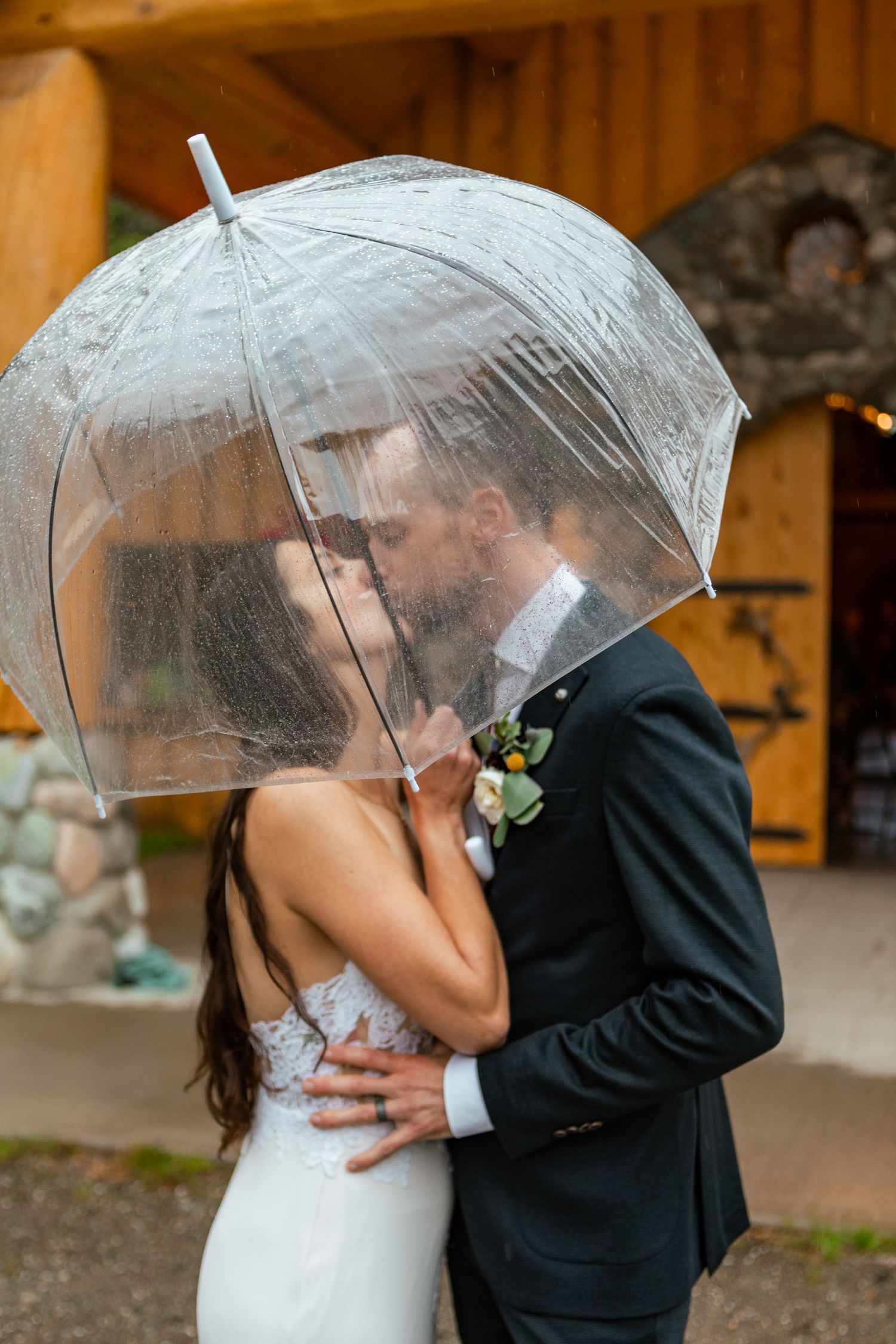 Romantic rainy day wedding portrait under clear umbrella at The Barn Matsu, Alaska.