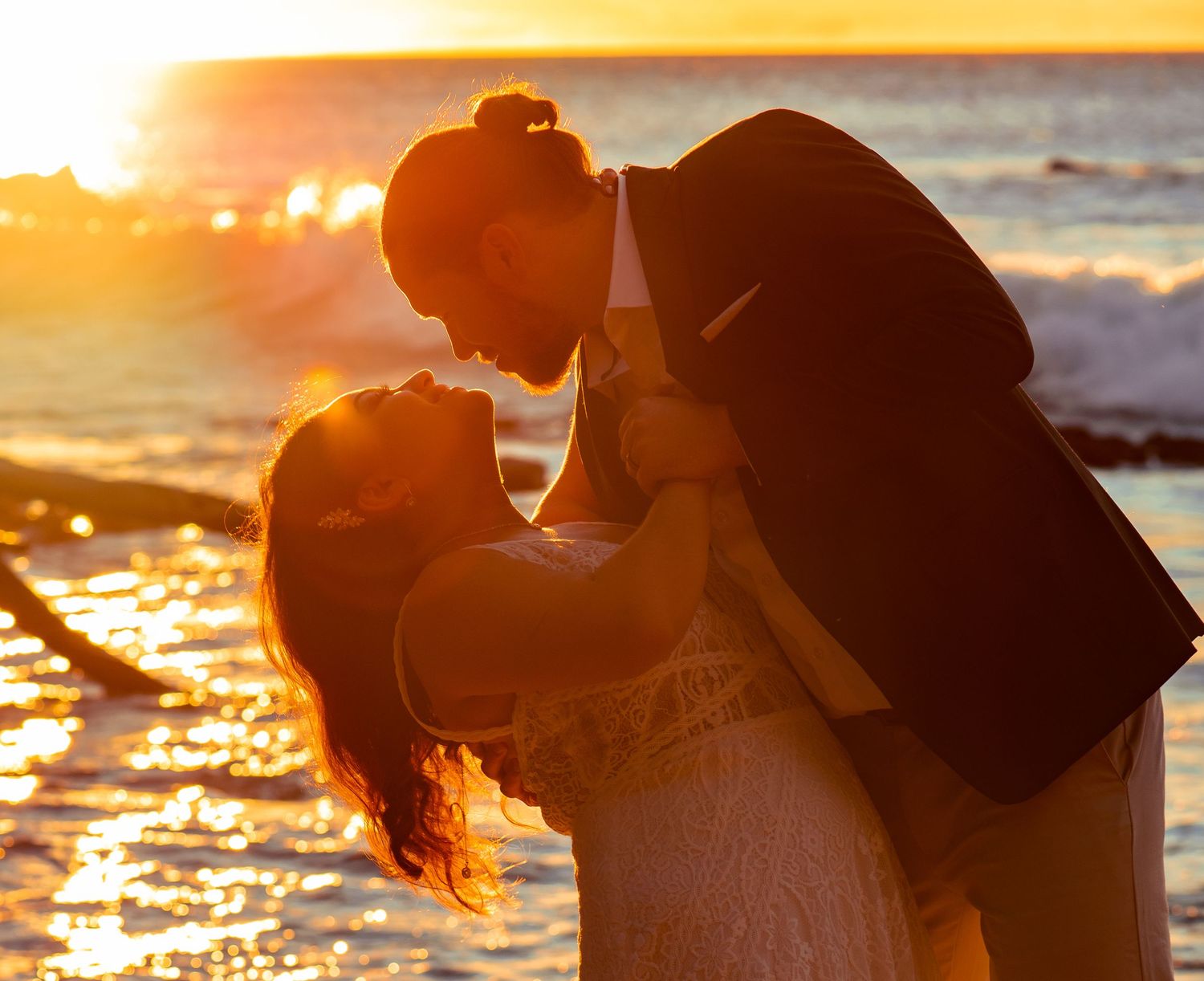 Romantic silhouette of a couple embracing against a golden sunset on the beach.