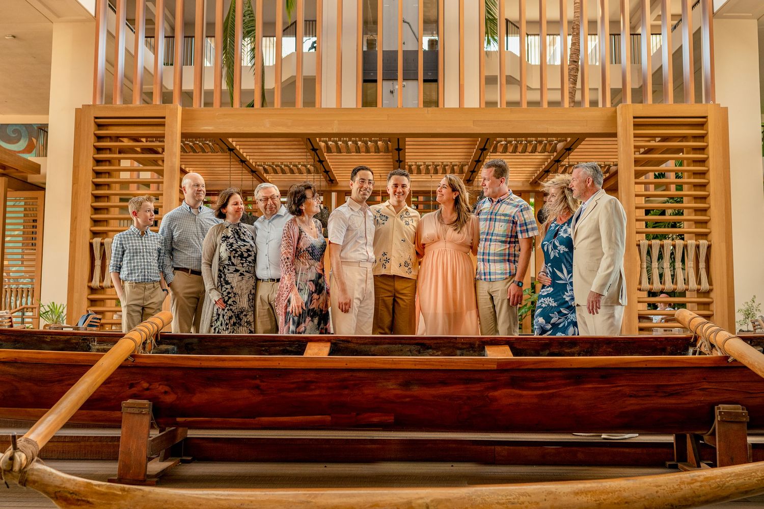 Group of people posing together indoors near a wooden canoe in a tropical venue.