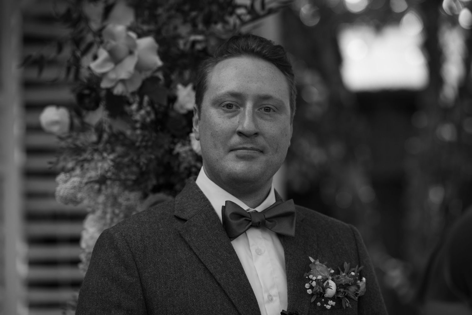 Black and white close up of groom crying as he sees bride walk down aisle.