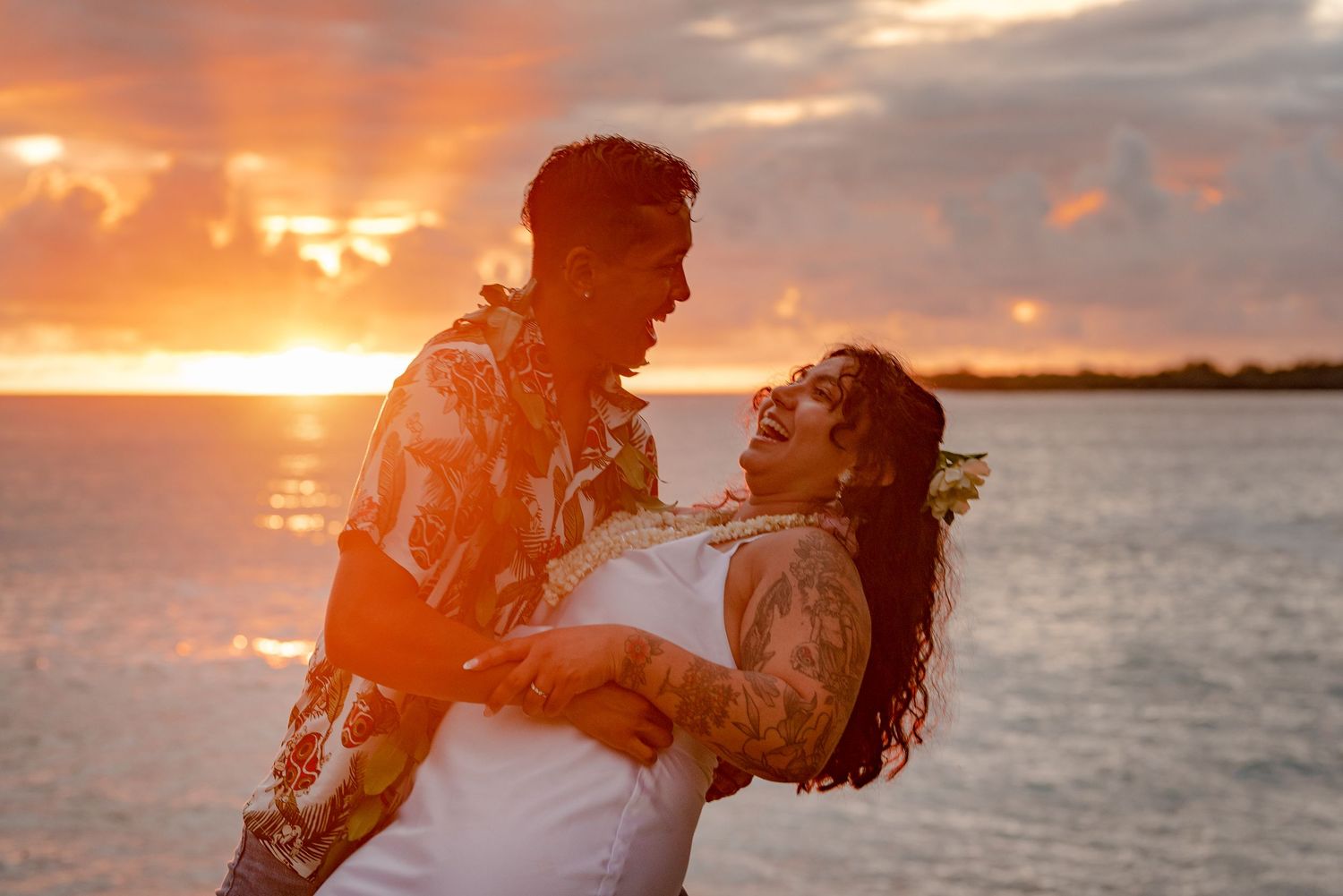 Couple sharing intimate moment against vibrant Kona ocean sunset.