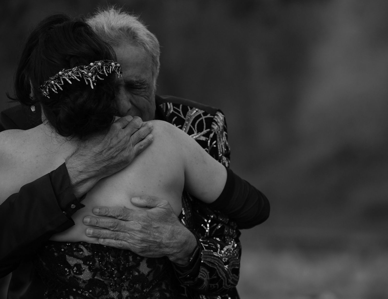 Emotional black and white embrace during wedding celebration.