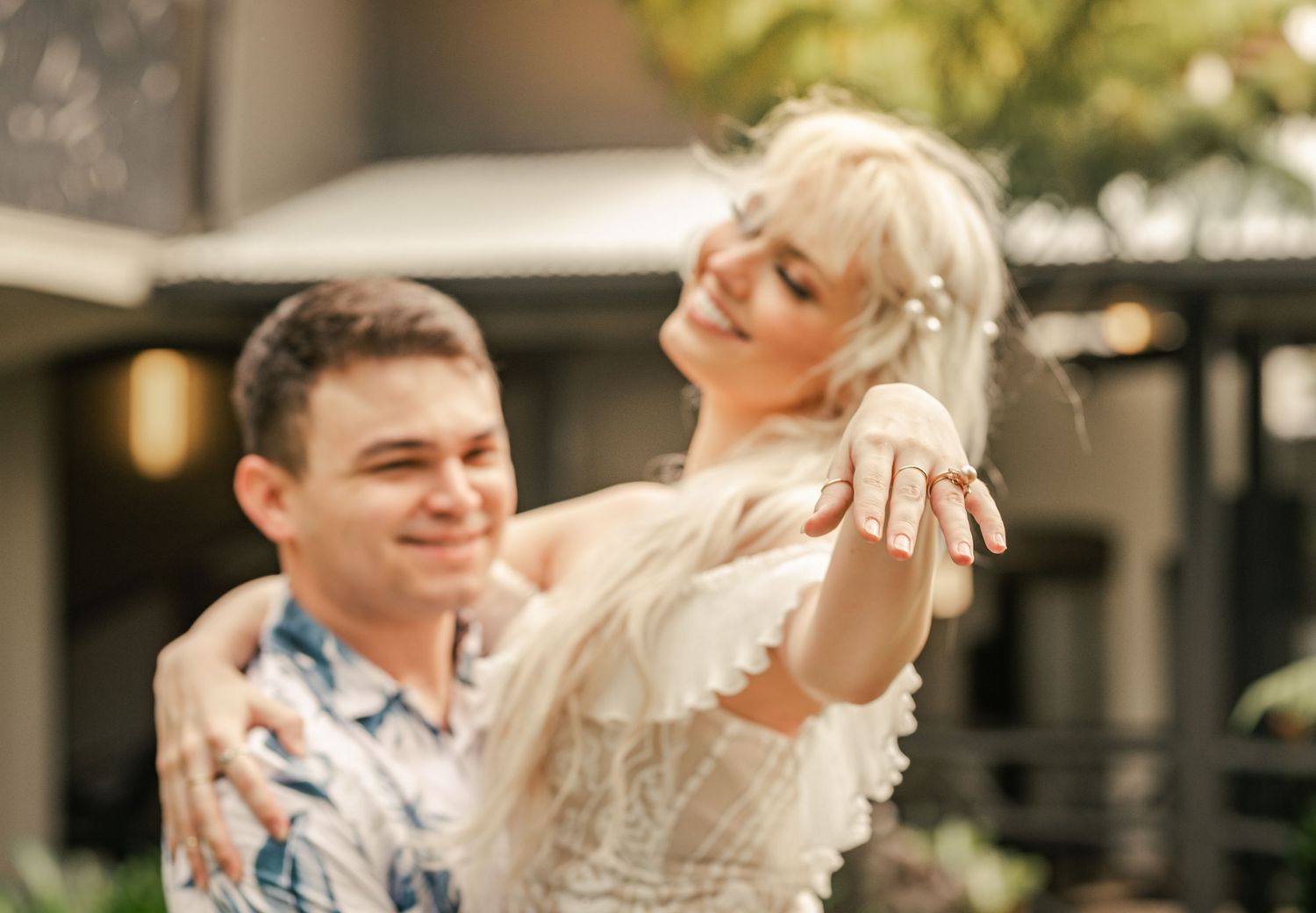 Joyful engagement moment captured outdoors with couple showing off ring.