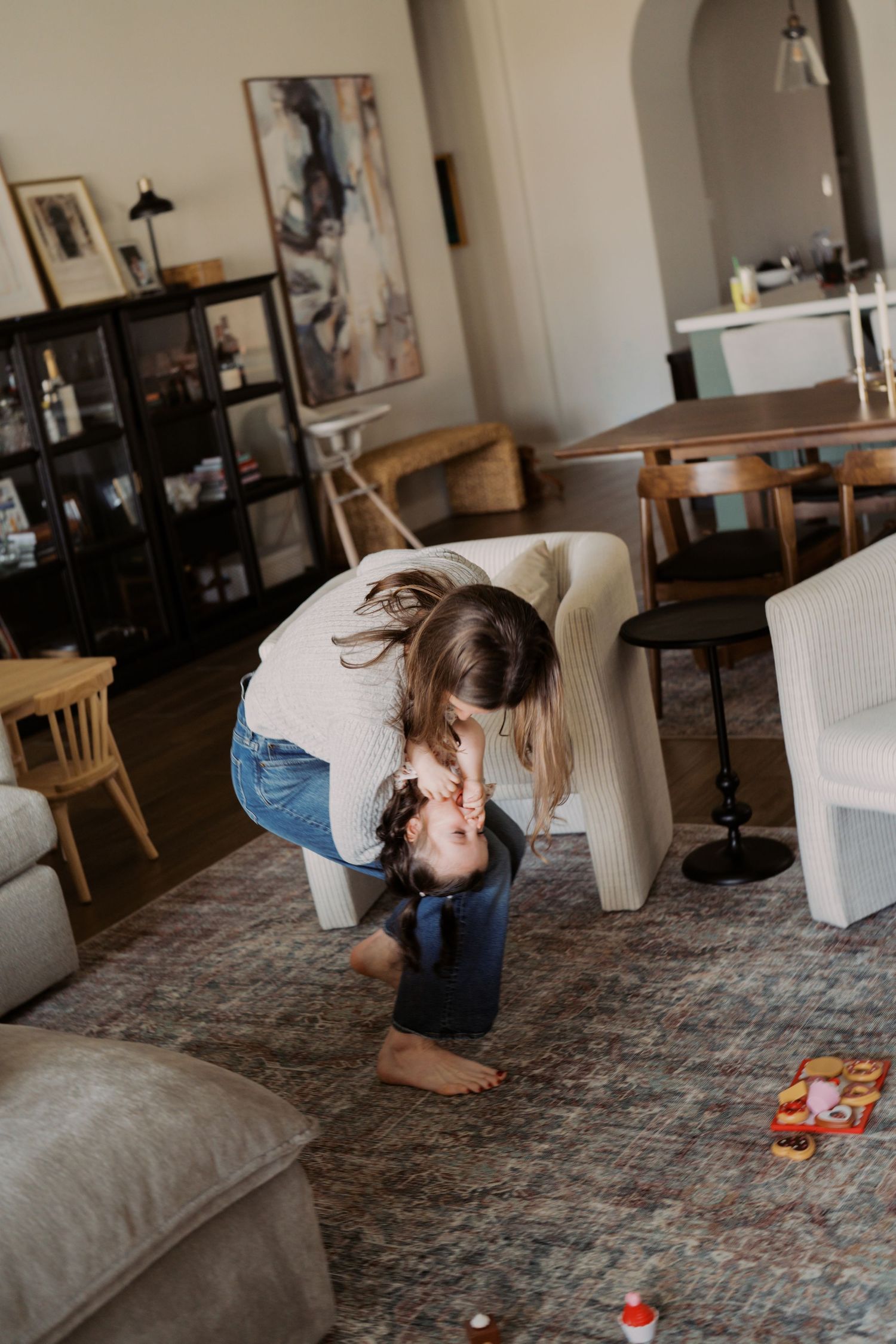 A sequence of photos showing someone bending down to pick up toys from a carpeted floor in a living room.