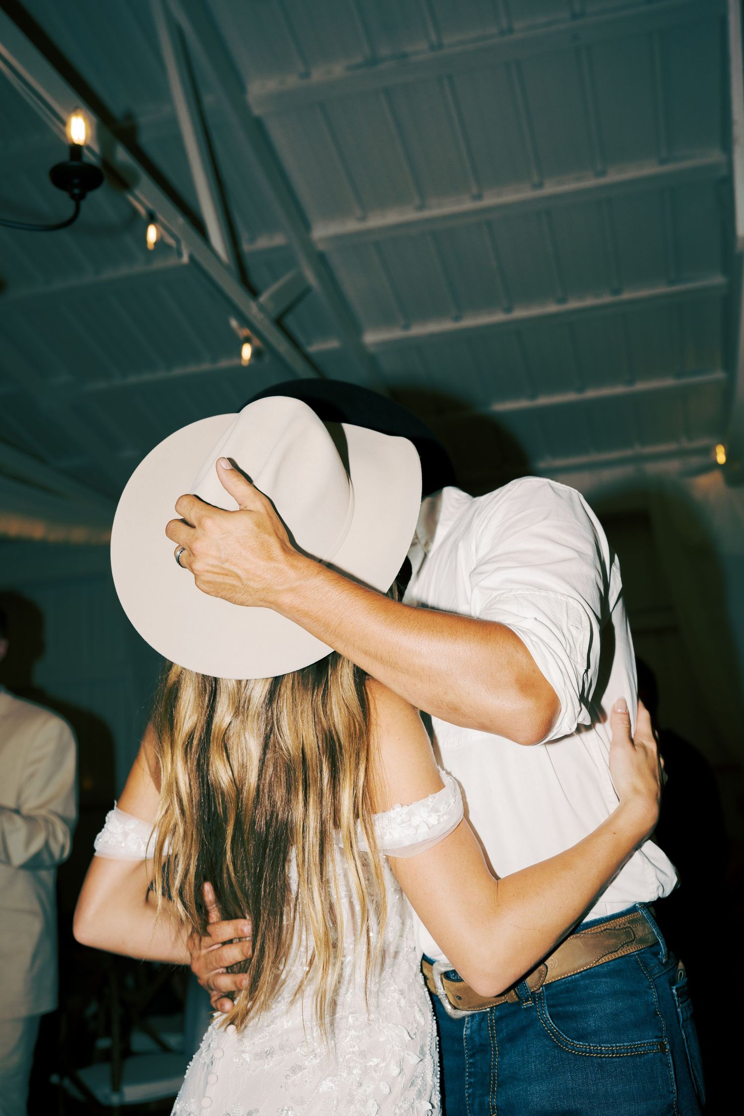 A romantic dance moment with a white cowboy hat obscuring a couple's embrace.