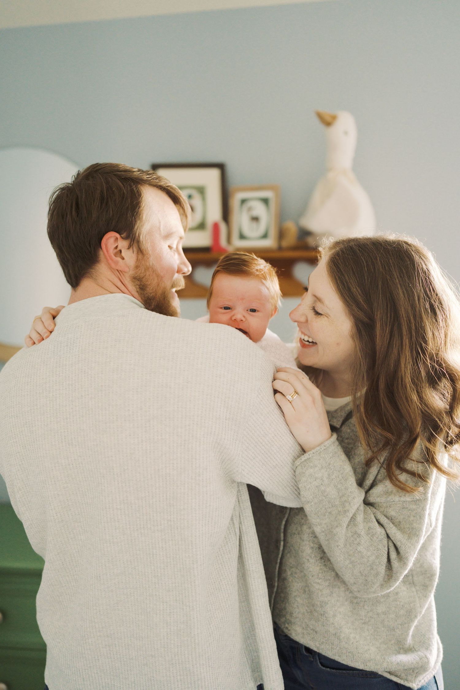 A family moment captured, with a man, woman, and baby embracing in a warm, loving embrace.