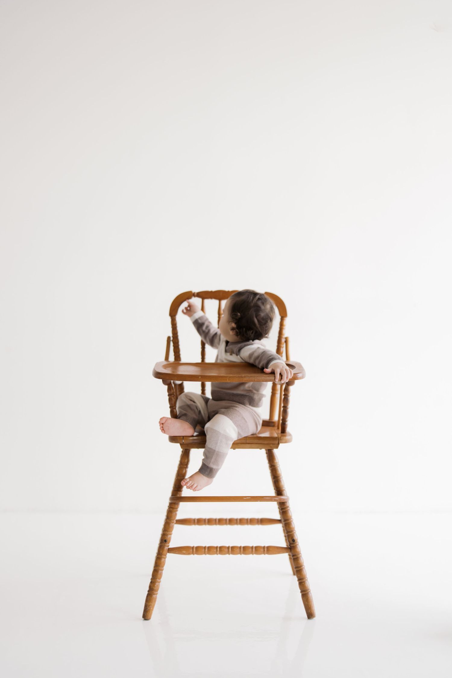 A stuffed animal sitting in a wooden high chair on a plain white background.