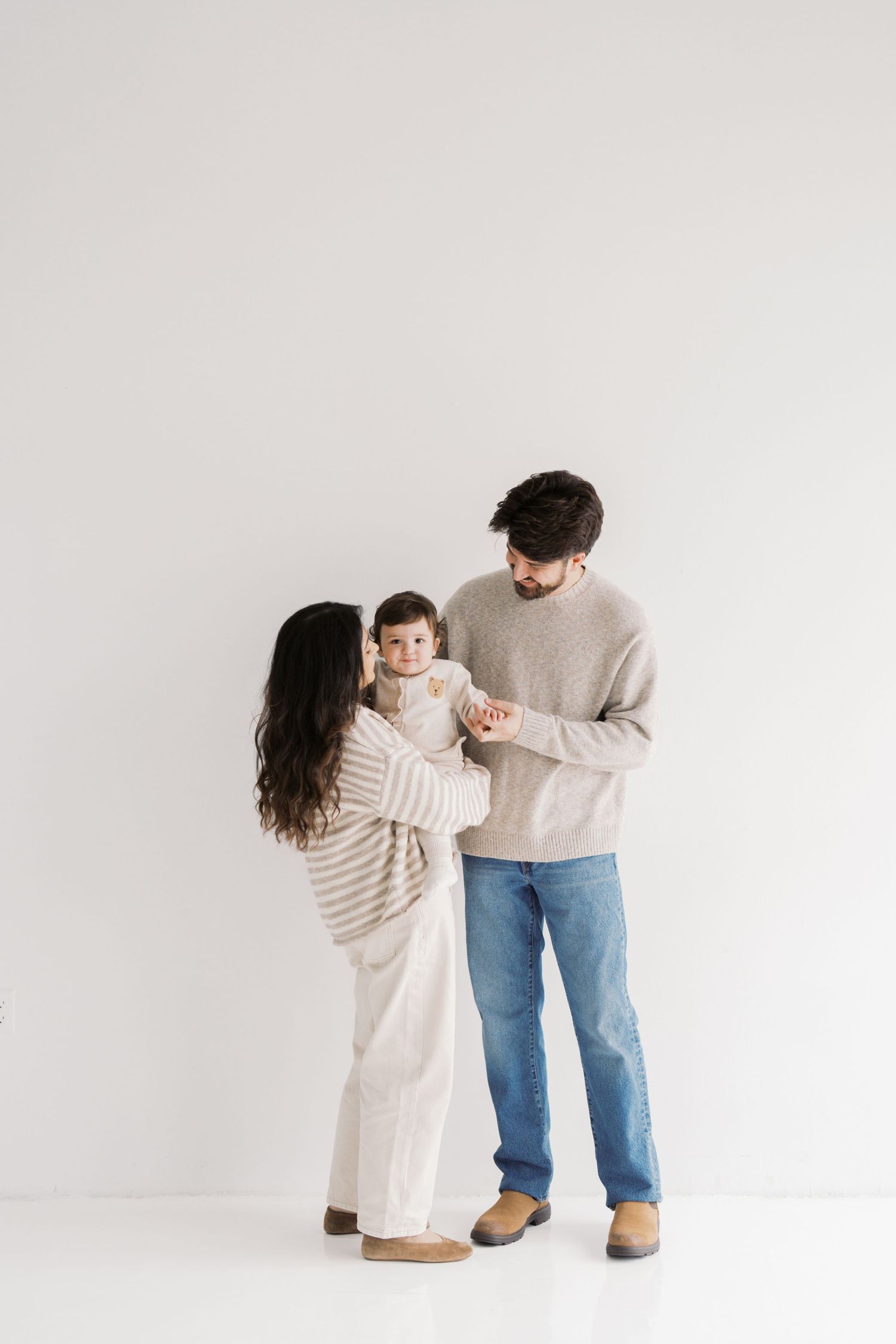 A man and a woman are holding a young child in a warm embrace.
