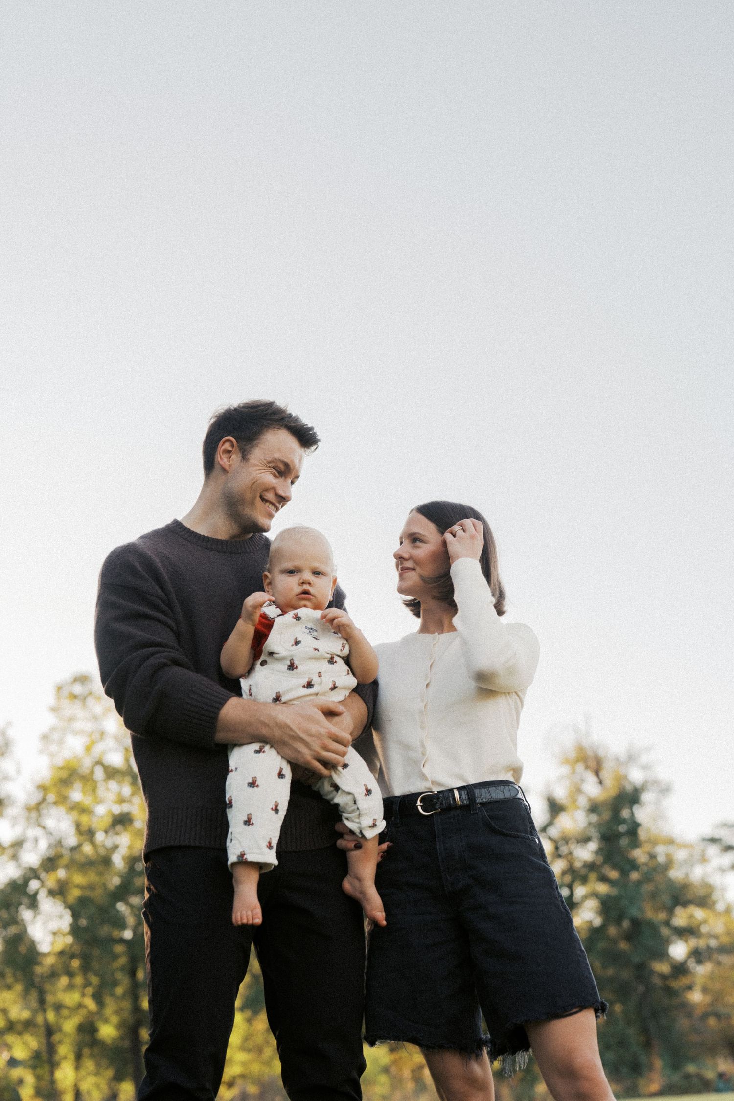 A family shares joyful moments together during an outdoor photo session with their baby in matching black and white outfits.