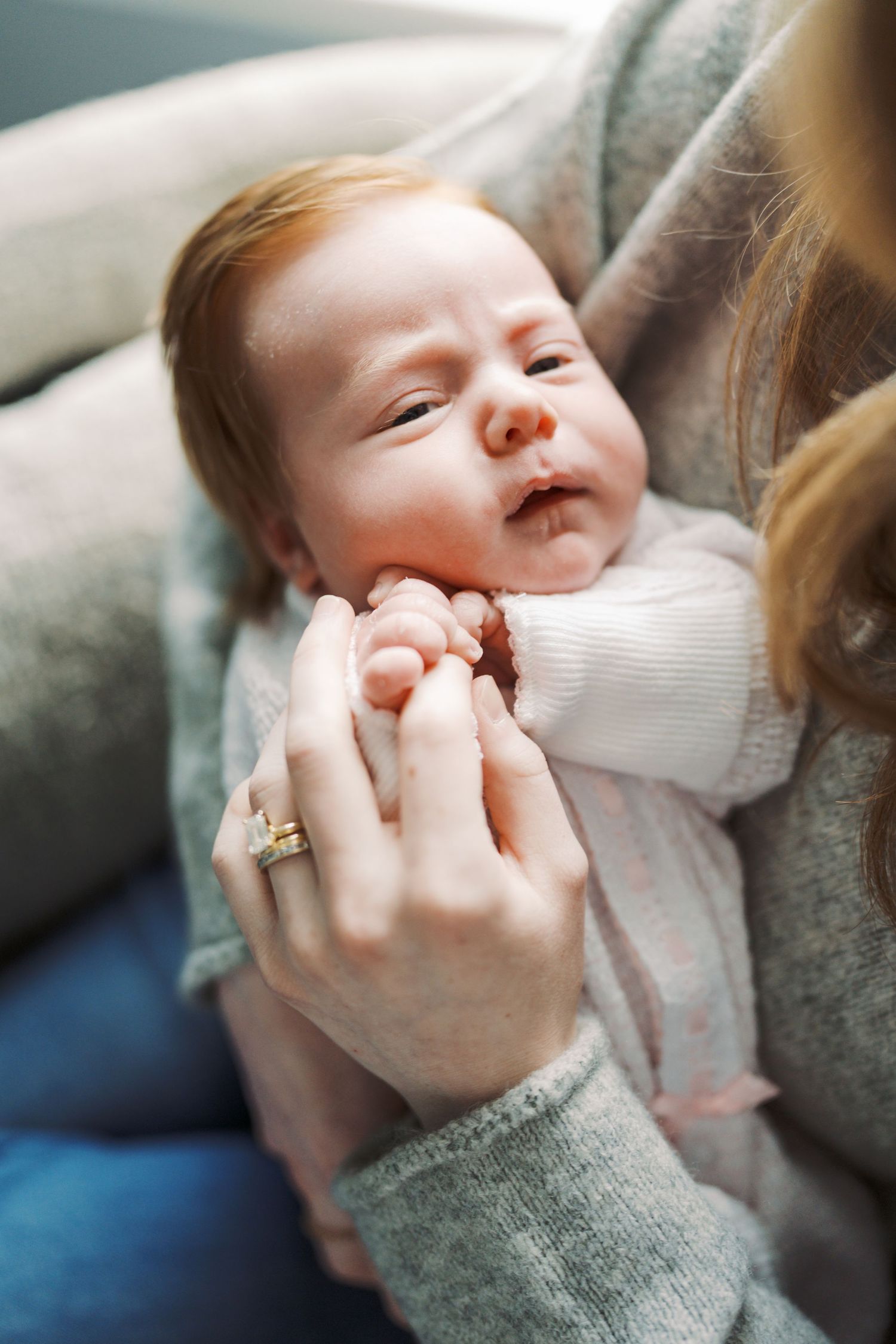A sleeping newborn baby is being gently held and comforted by a person's hands.