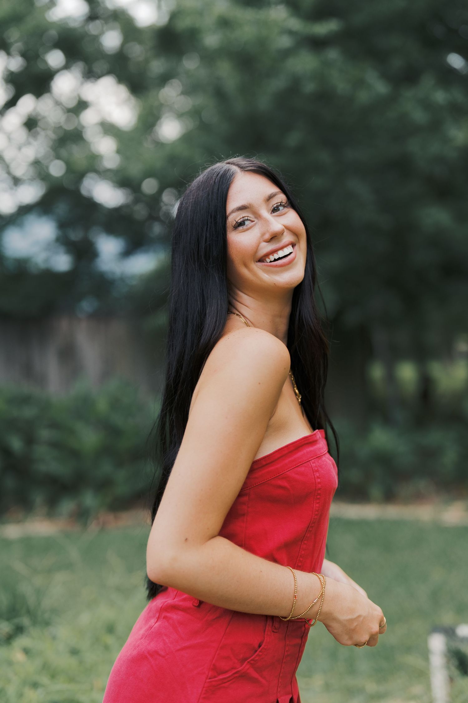 Person in red dress laughing outdoors with natural garden background.