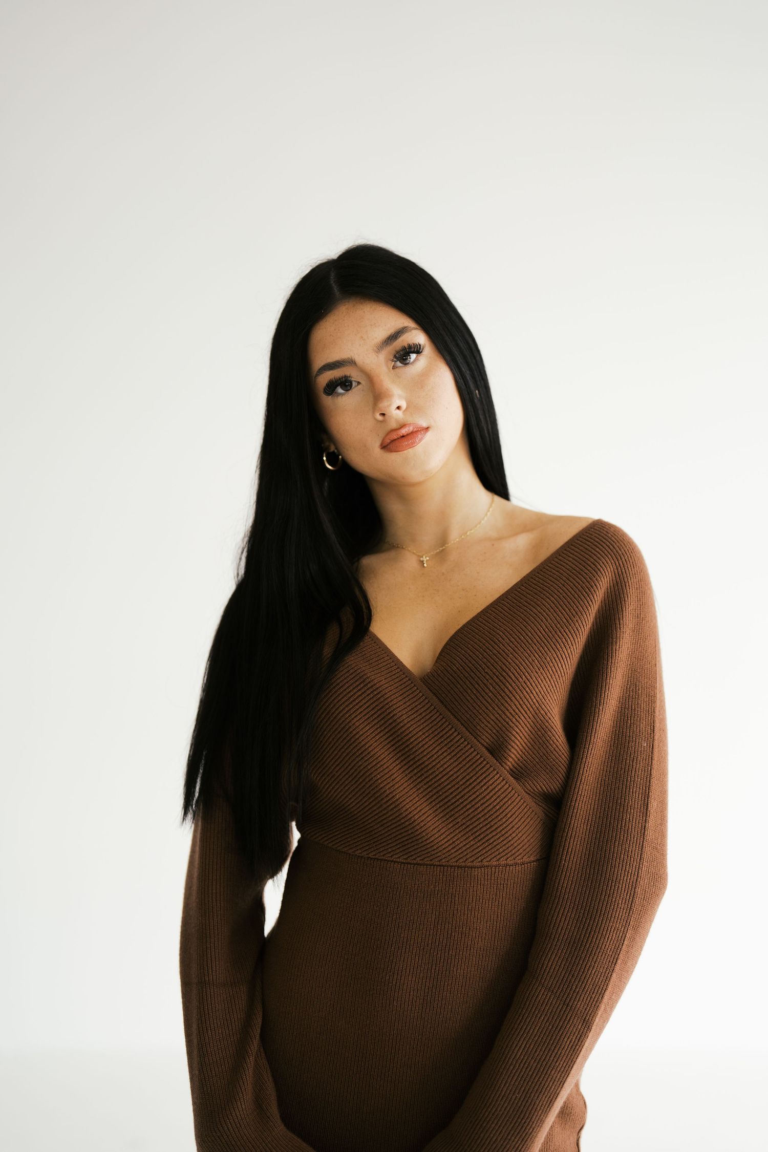 A fashion portrait series featuring someone in a brown asymmetrical sweater against a white background.