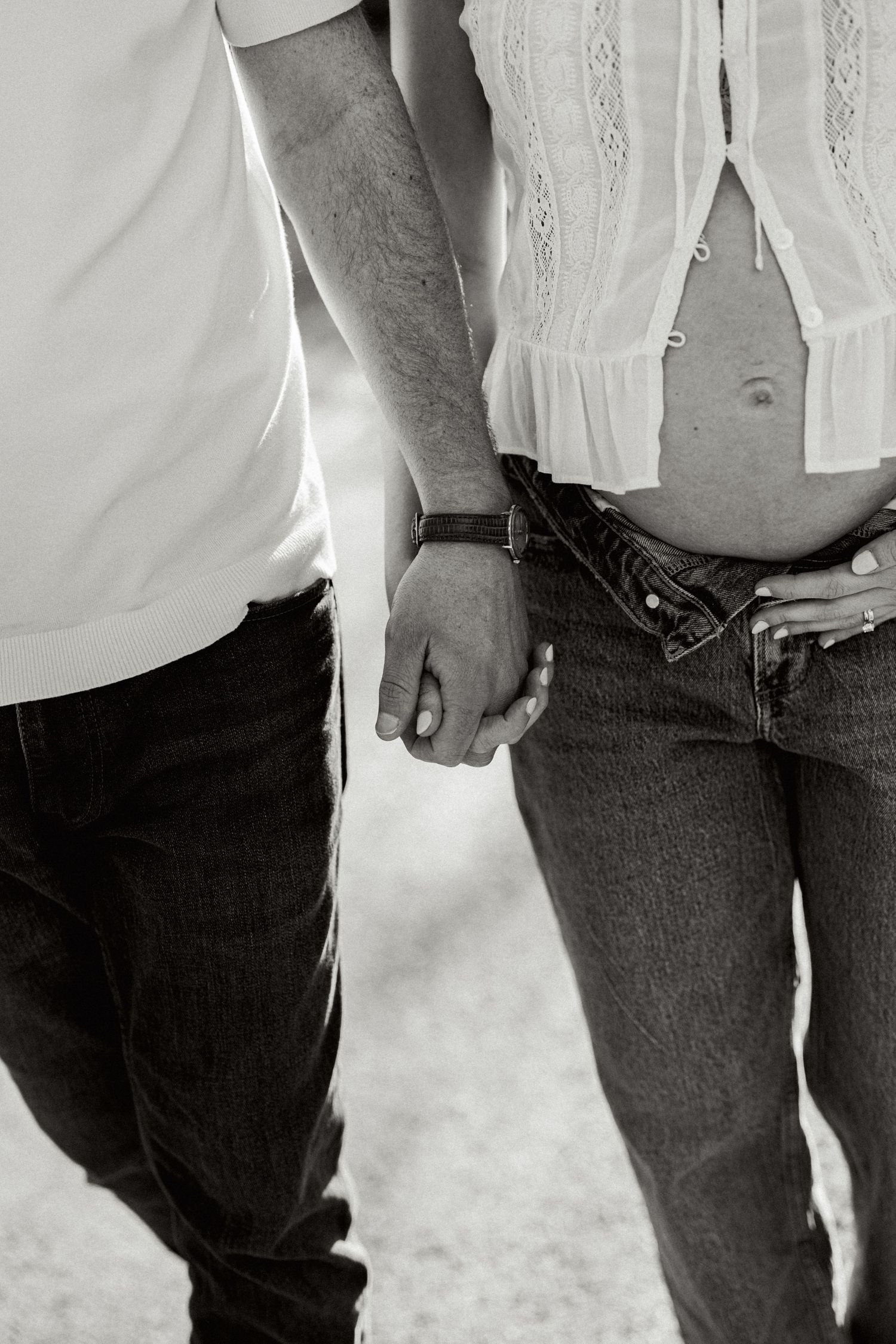 A black and white image showing the lower body of a person wearing jeans and a white lace-trimmed garment.