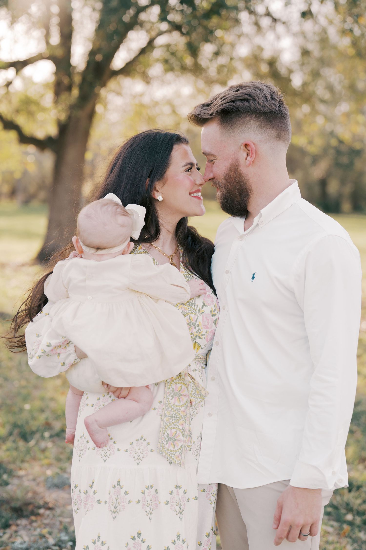 Family sharing intimate moment outdoors in soft sunlight.