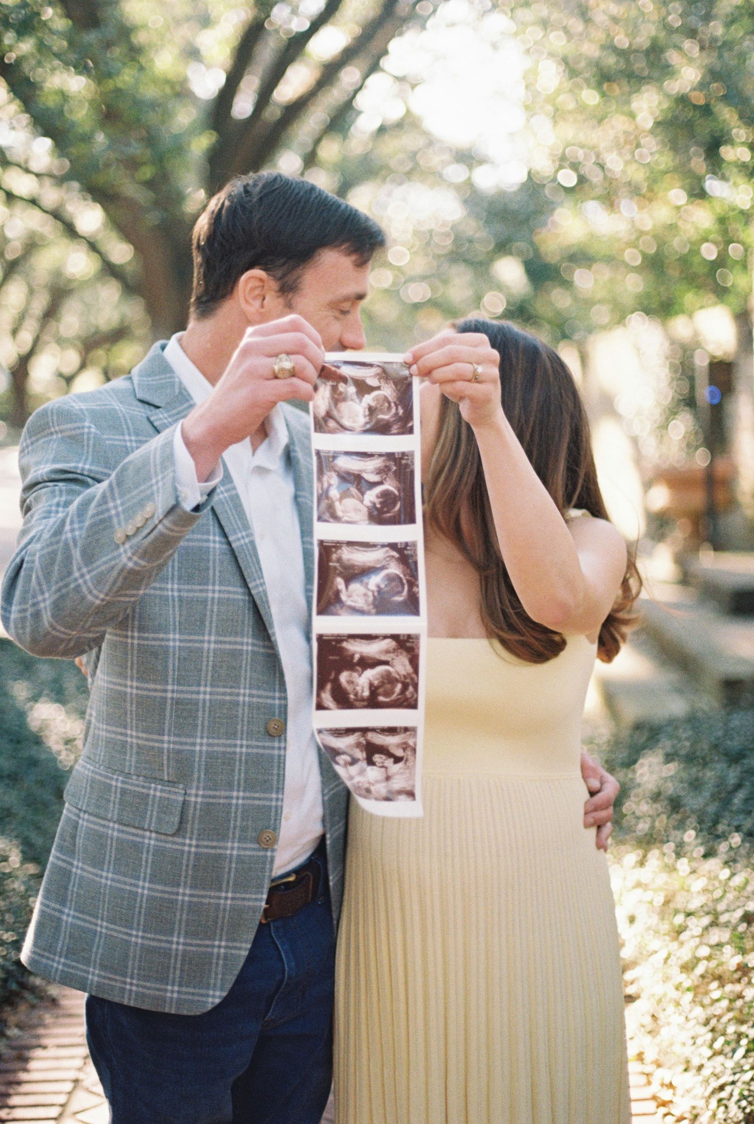 A couple is looking at an ultrasound image while standing in a park.