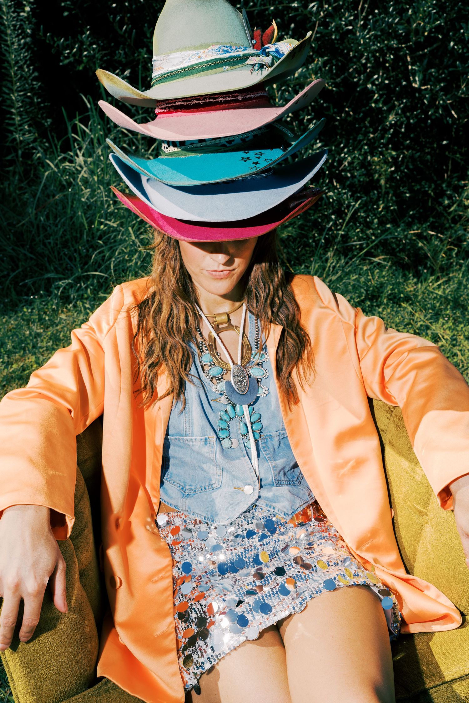 A series of fashion photos featuring a person wearing an orange jacket and floral outfit while sitting outdoors in nature.